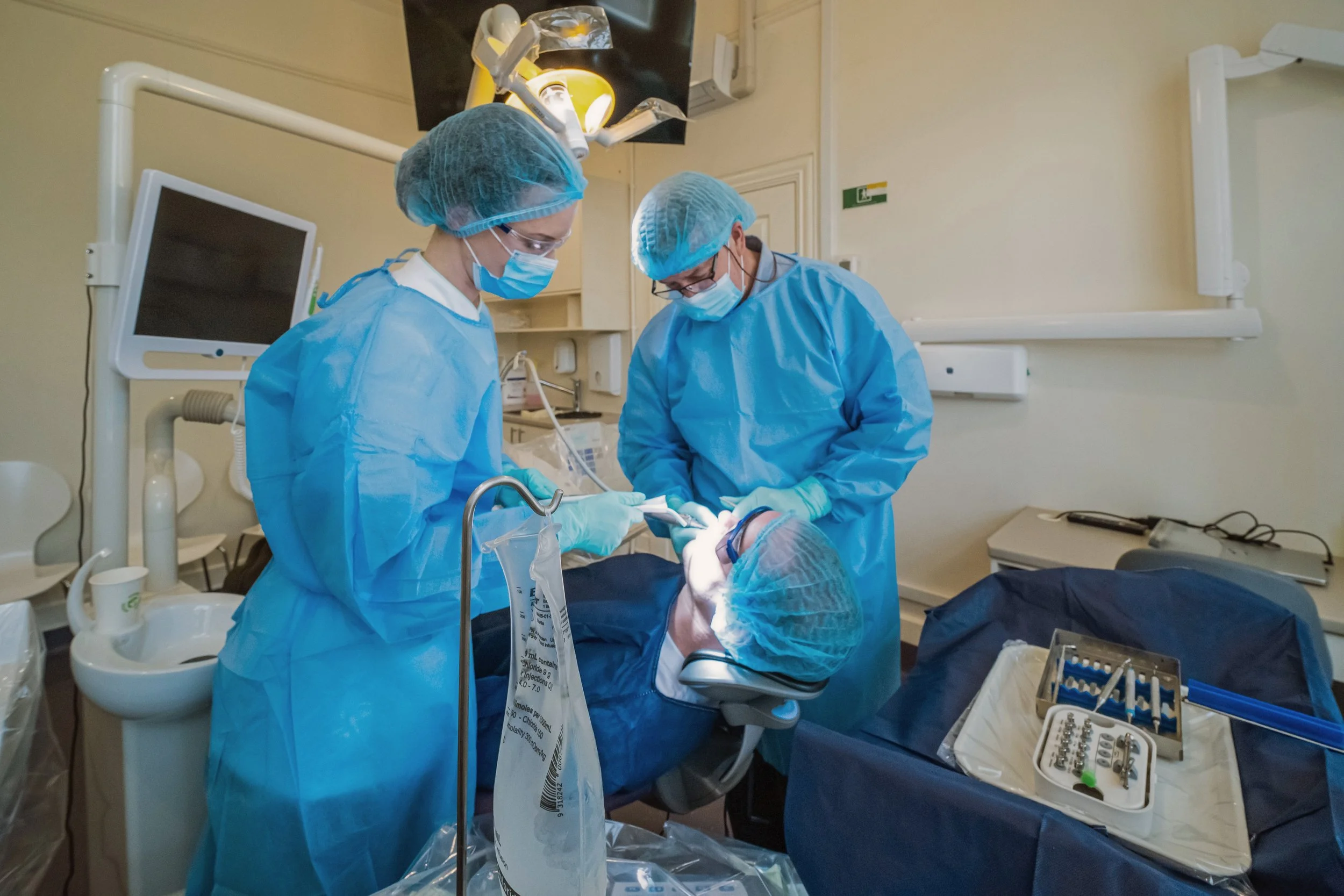 Medical team performing a surgical operation in an operating room, with the patient lying on the operating table and medical equipment nearby.
