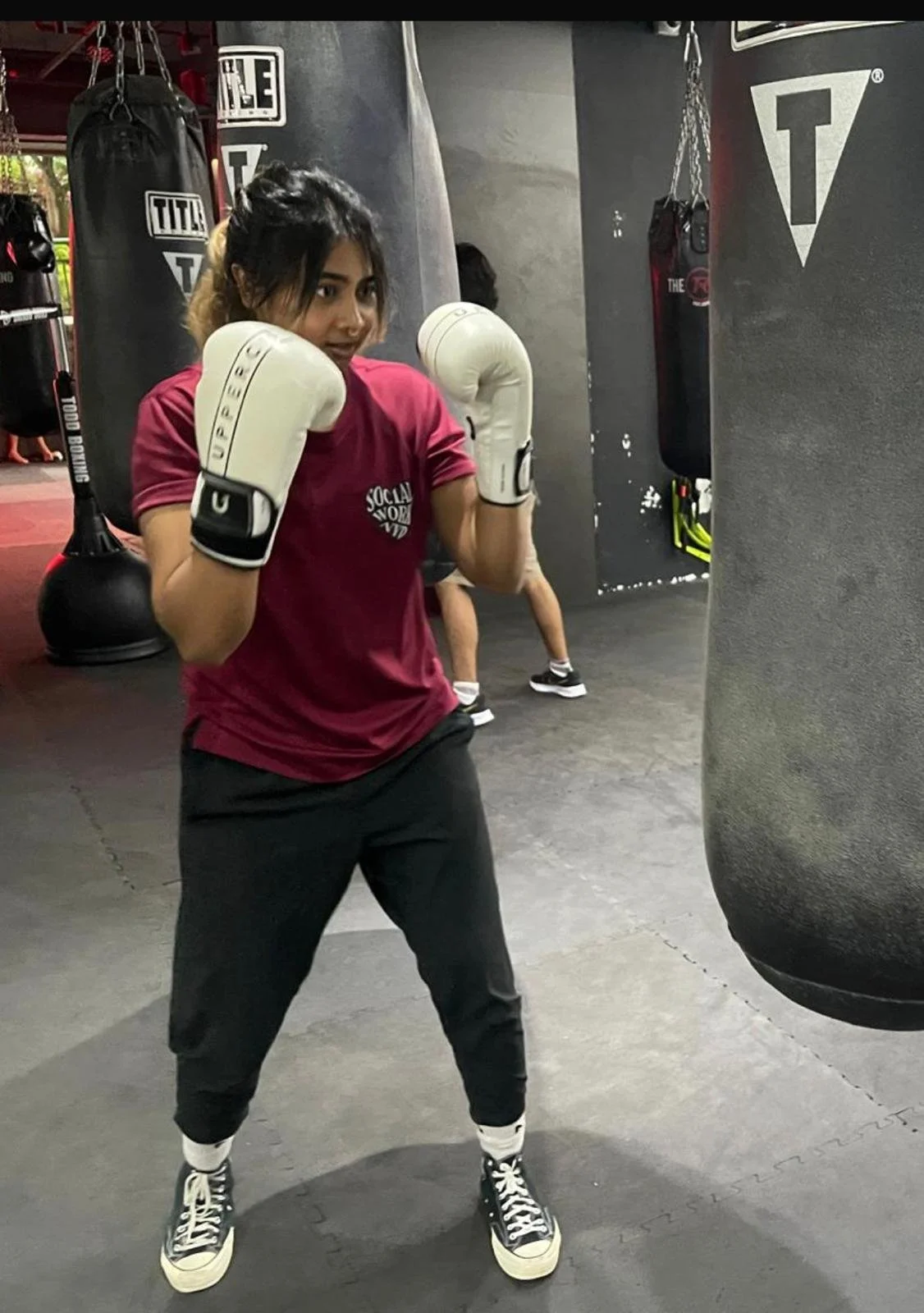 Coach Qaila demonstrating a boxing stance during youth MMA fitness training in Singapore.