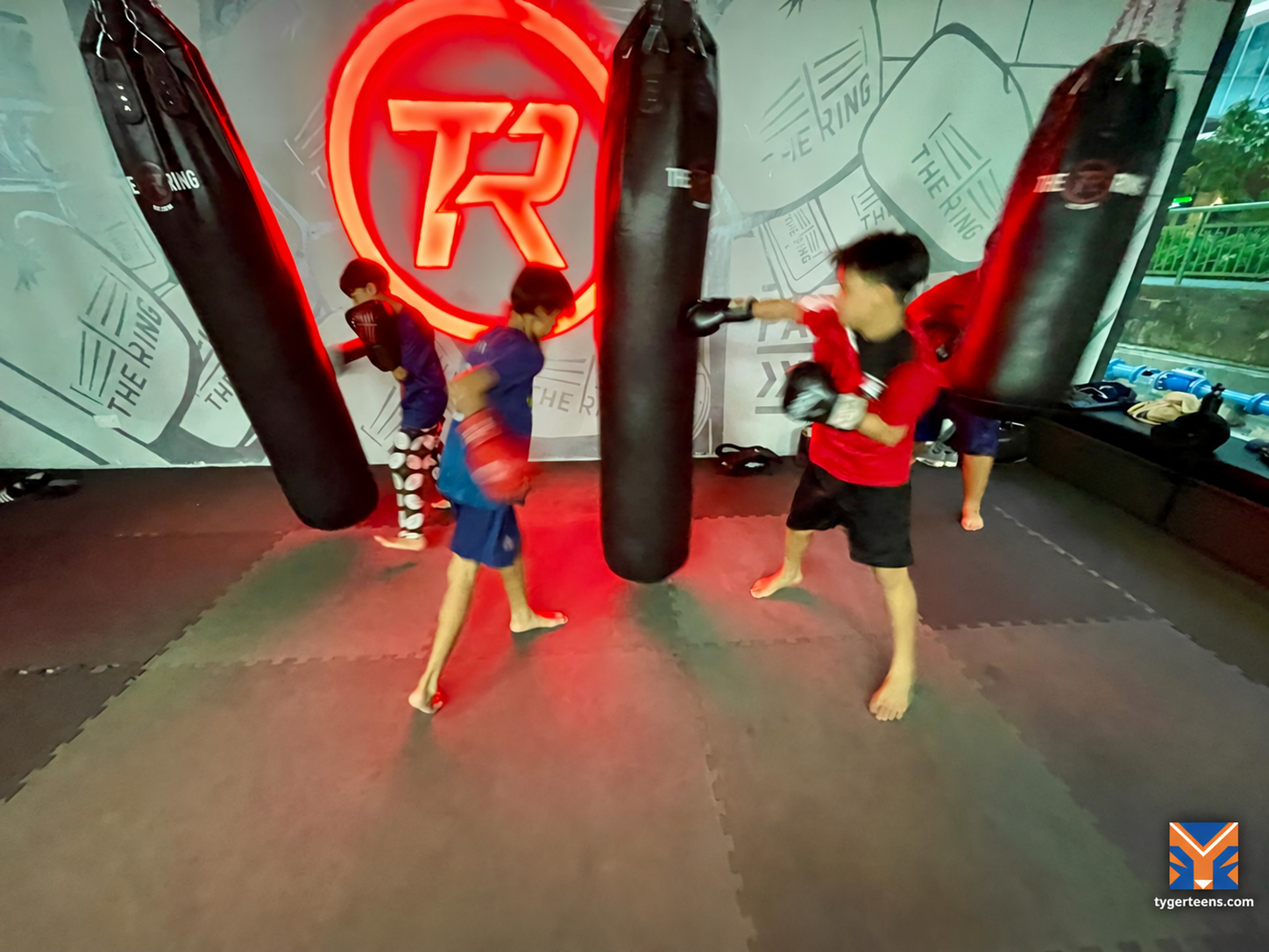 Young people practise boxing fitness using individual training bags.