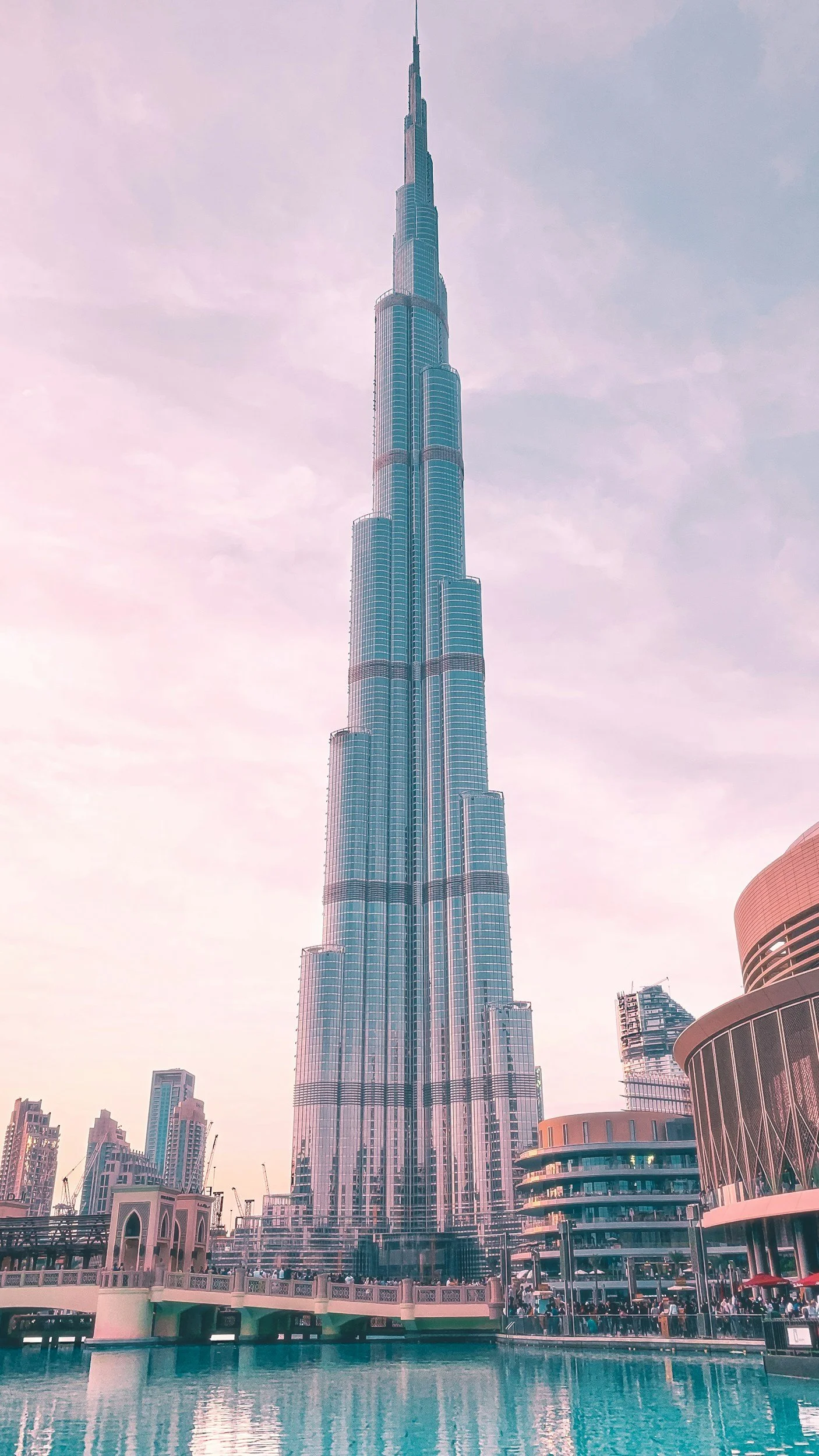 Le Burj Khalifa, la plus haute tour du monde, à Dubaï, vue depuis un plan d'eau avec bâtiments modernes autour.