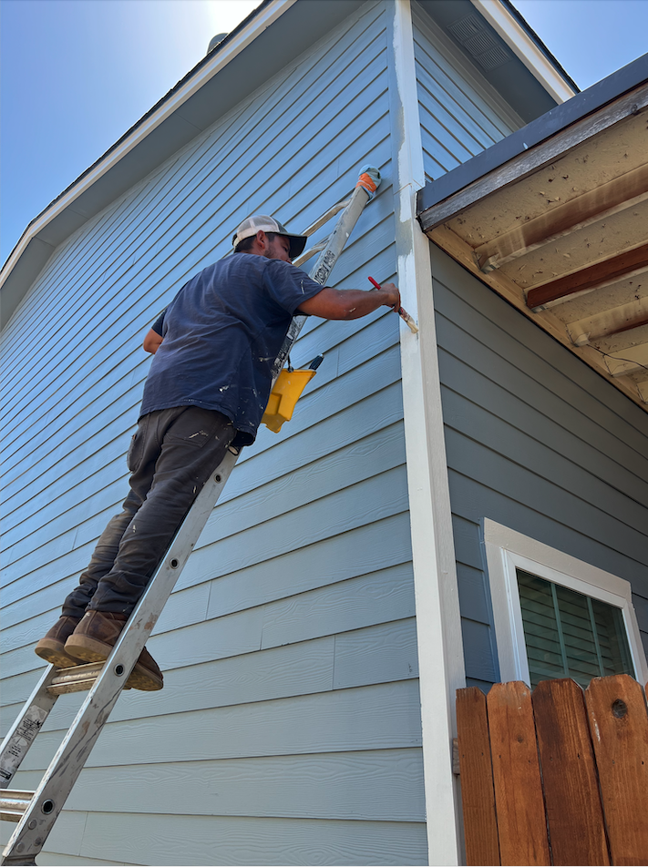 Professional painter painting exterior siding on a San Antonio home