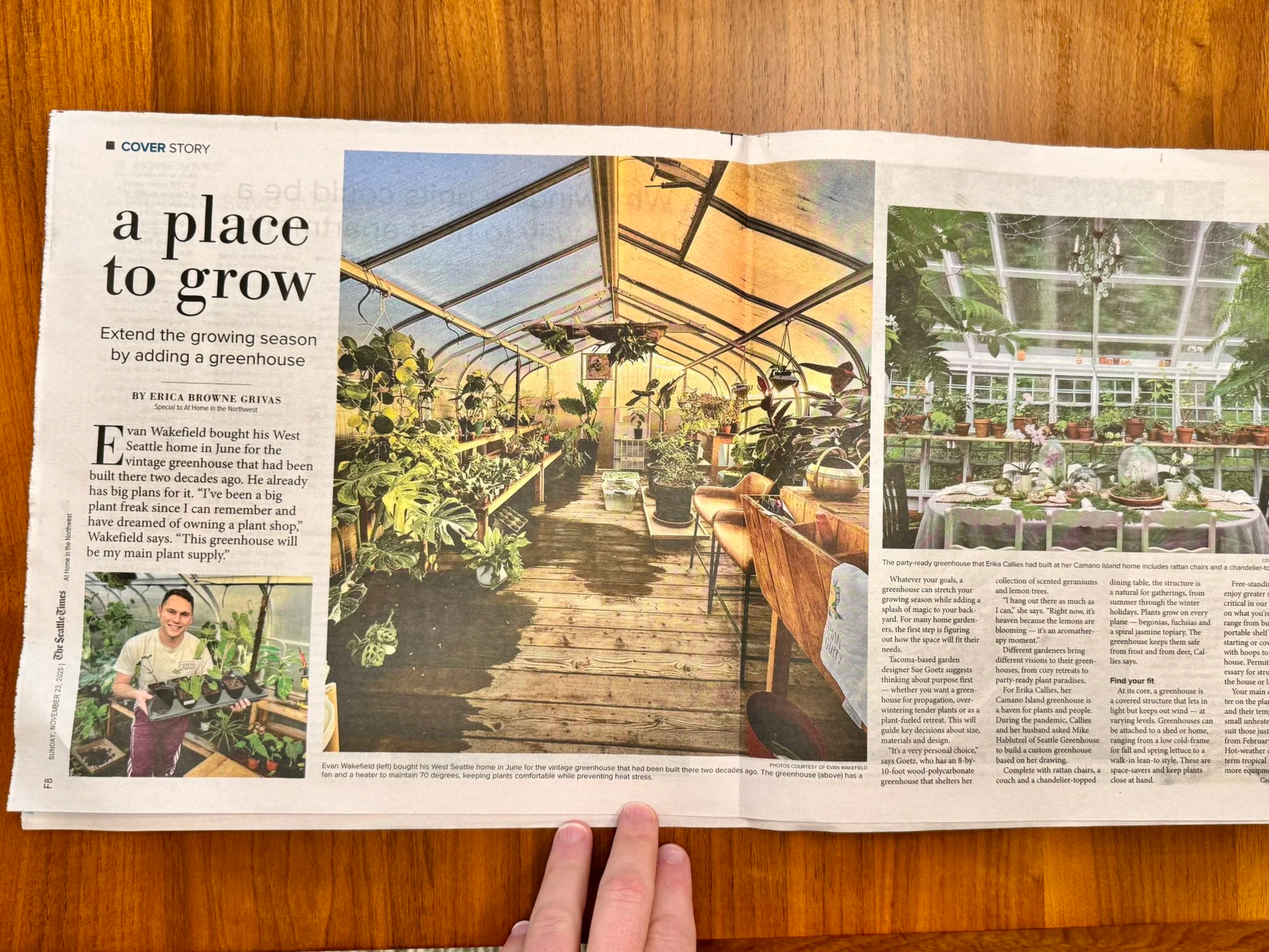 A newspaper page with a story about a greenhouse, showing indoor greenhouse photos and a man holding plants, with a hand at the bottom holding the page.