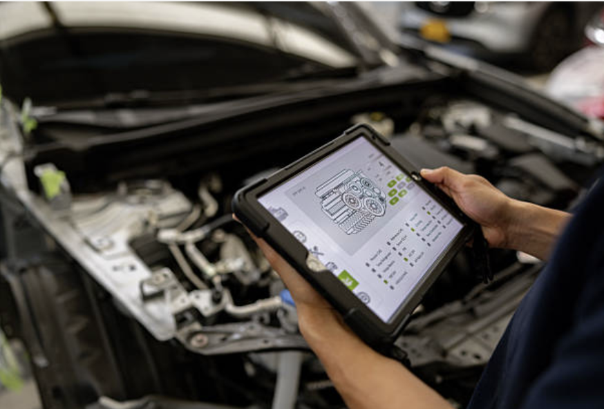 mechanic inspecting a car engine with a scanner showing an engine diagnostic chart in a auto repair shop.