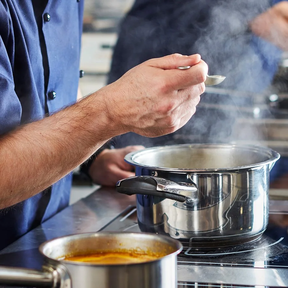 Chef tasting a quality stock in a stock pot