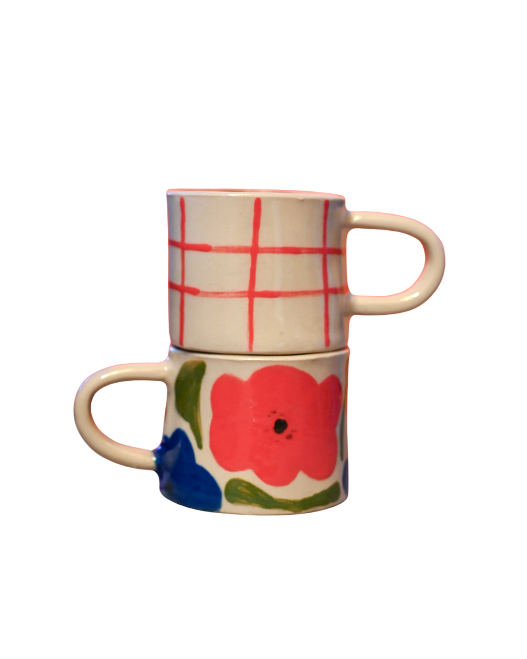 Zwei stapelbare Keramik-Tassen, die obere Tasse hat ein rotes Kästchenmuster, die untere Tasse ist mit einer großen roten Blume und grünen Blättern bemalt.