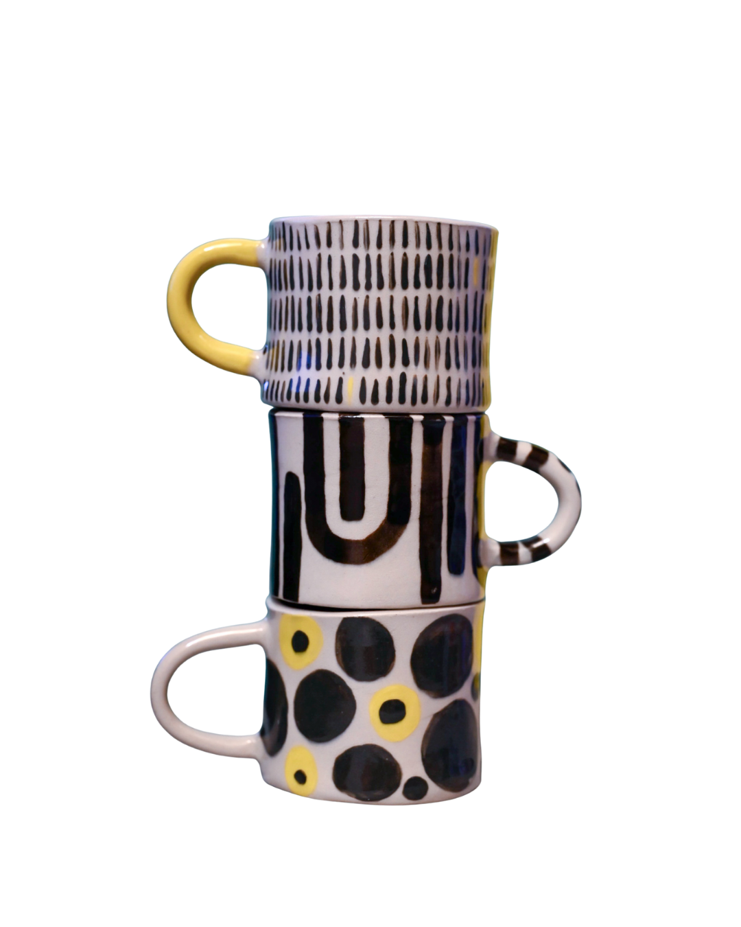 Drei gestapelte Keramikbecher mit kreativen, schwarzen und gelben Mustern auf weißem Hintergrund, isoliert auf schwarzem Hintergrund.