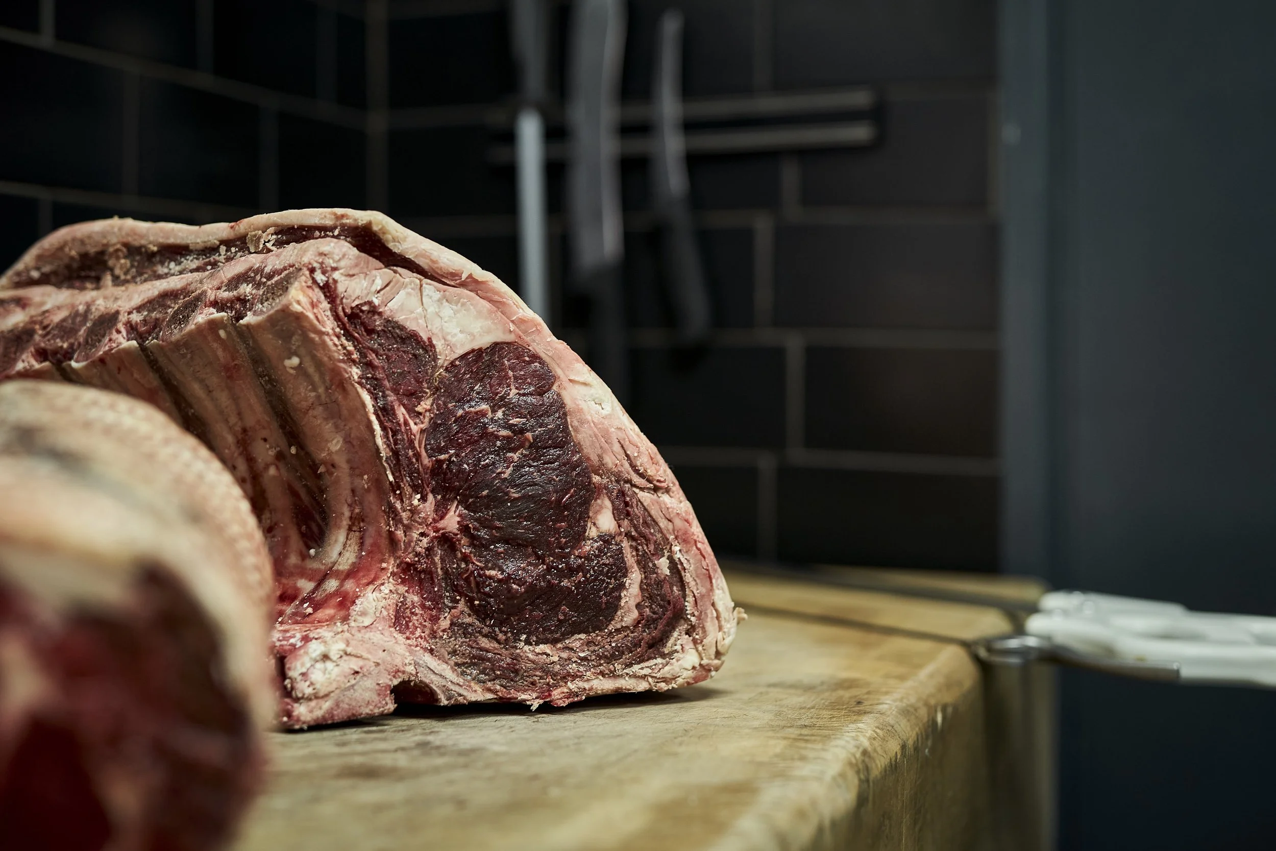 Large raw cut of beef brisket on a wooden butcher block in a meat shop.