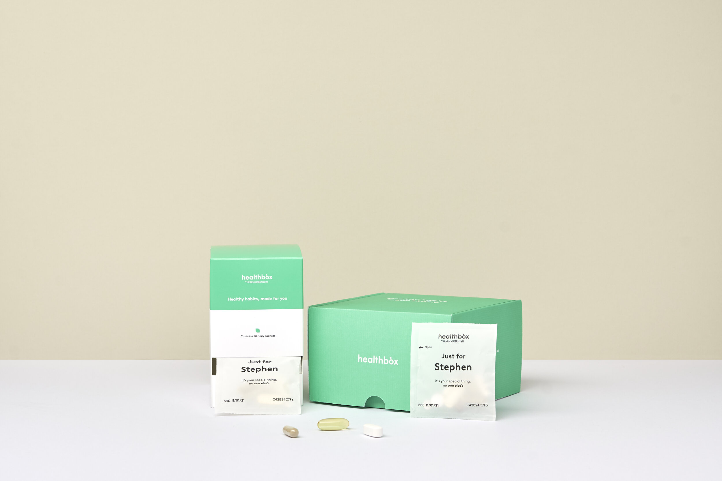 Healthbox supplement packages and capsules on a white surface against a light beige background.