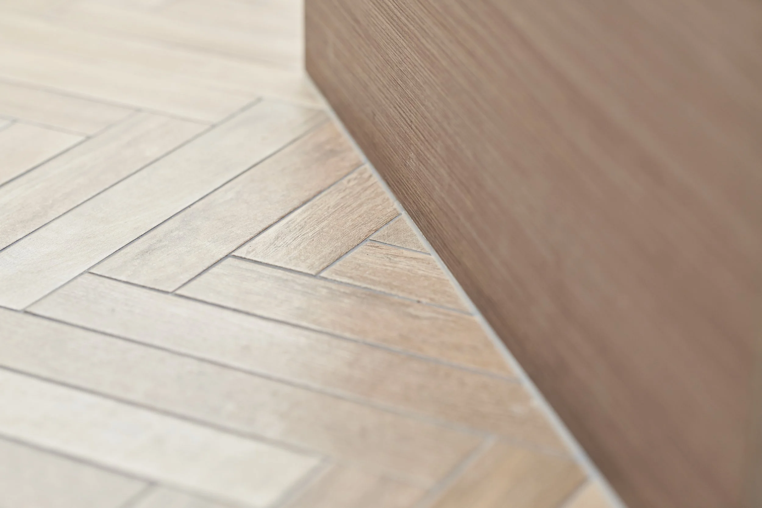 Close-up of a wooden baseboard at the intersection of wooden and tile flooring.