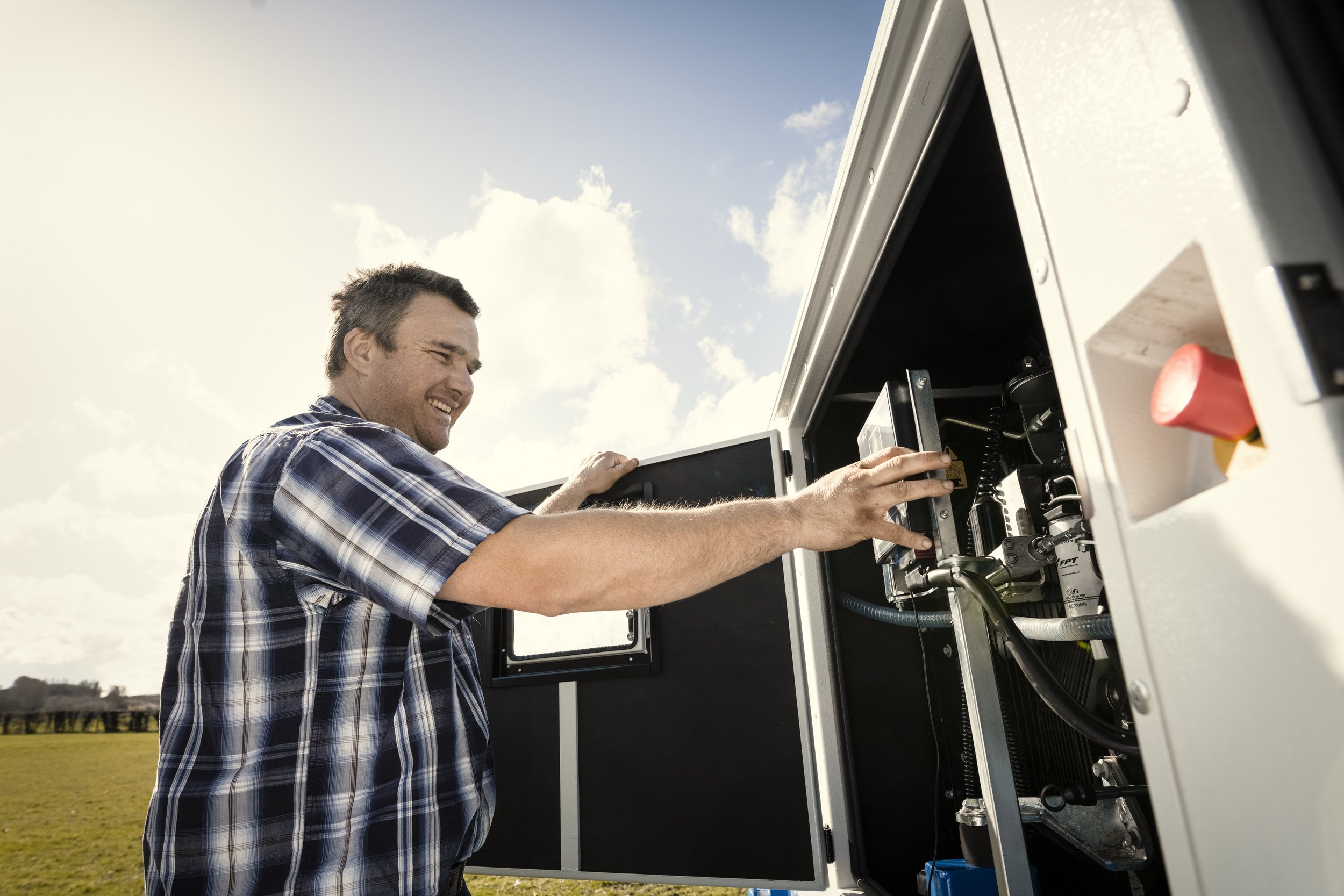 Man in plaid shirt working on a mechanical or electronic device outdoors