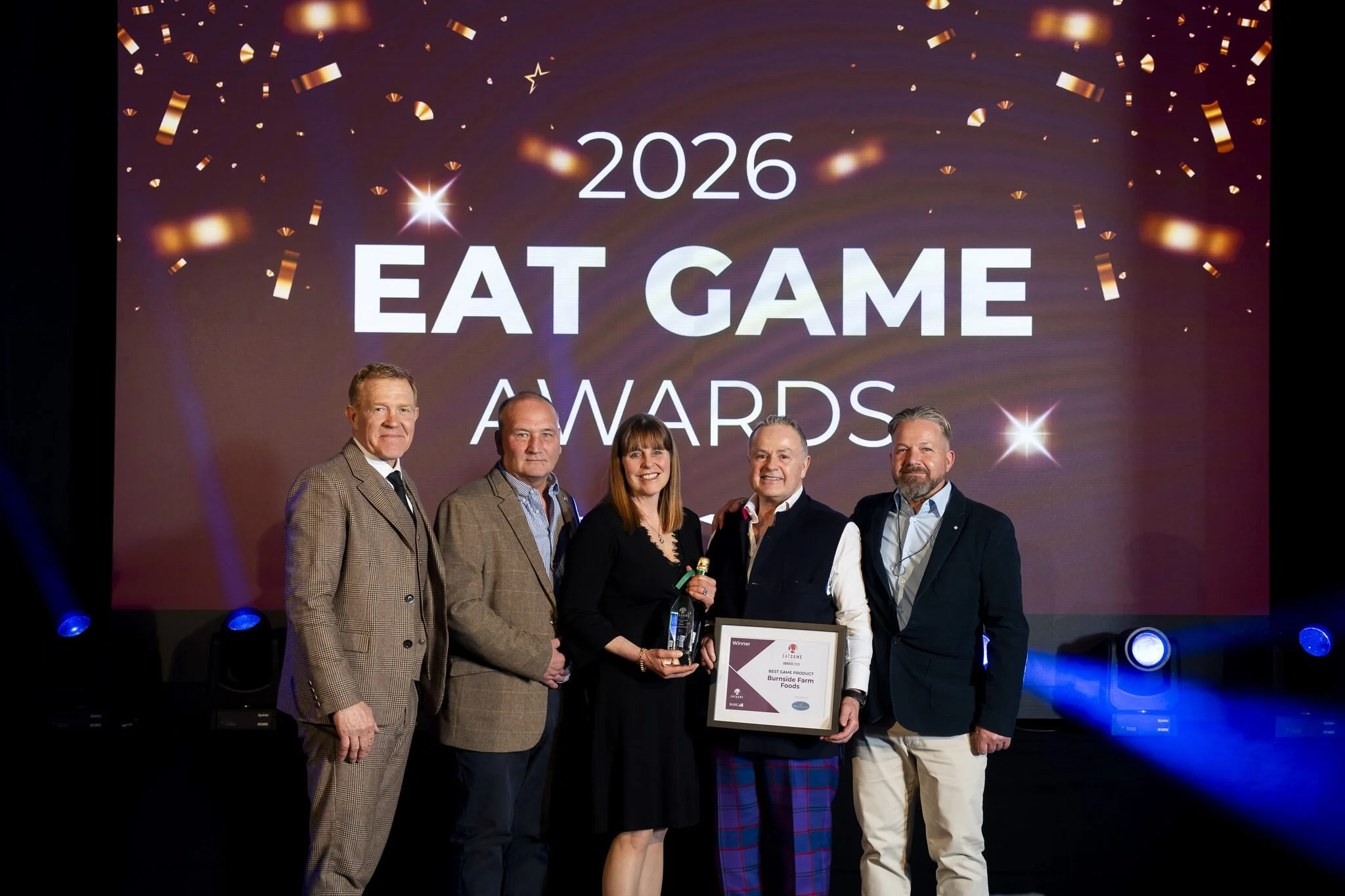 Group of five people standing on stage at the 2026 Eat Game Awards, with one holding a framed award.
