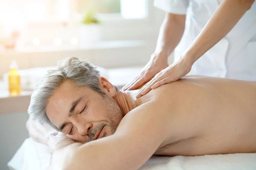 Man receiving a back massage in a bright, relaxing room.