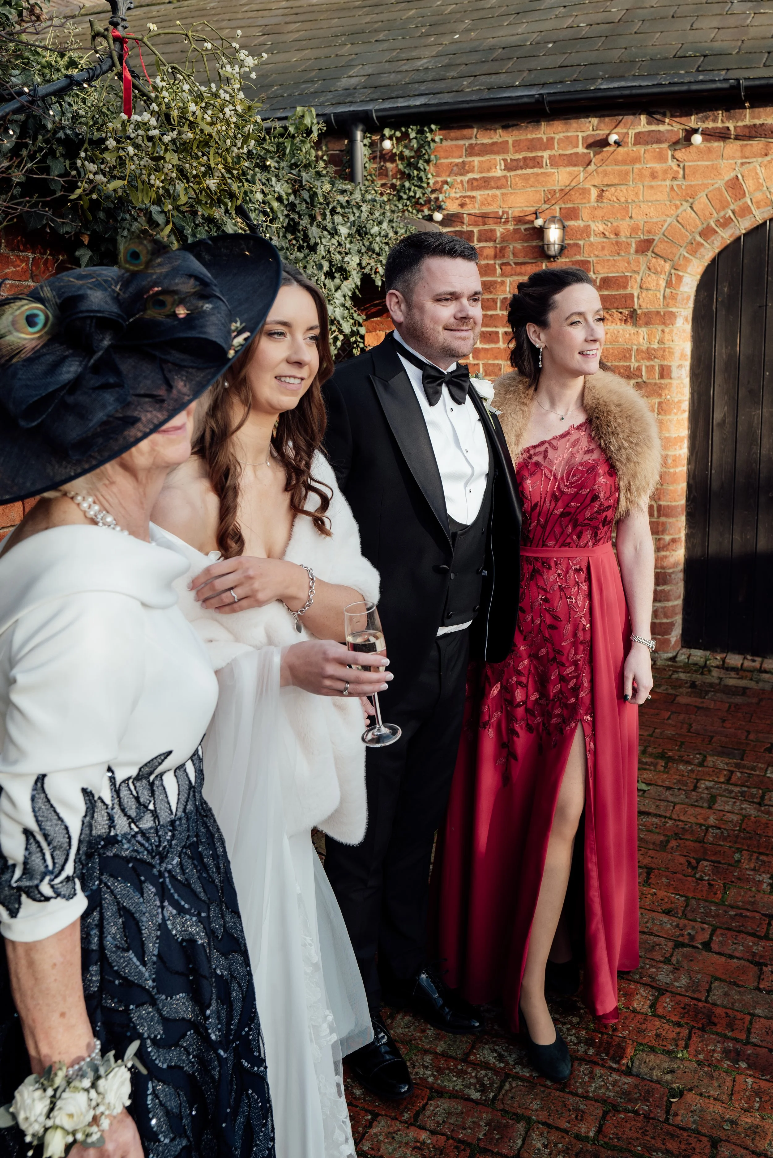 People dressed in formal attire standing together outdoors against a brick wall.