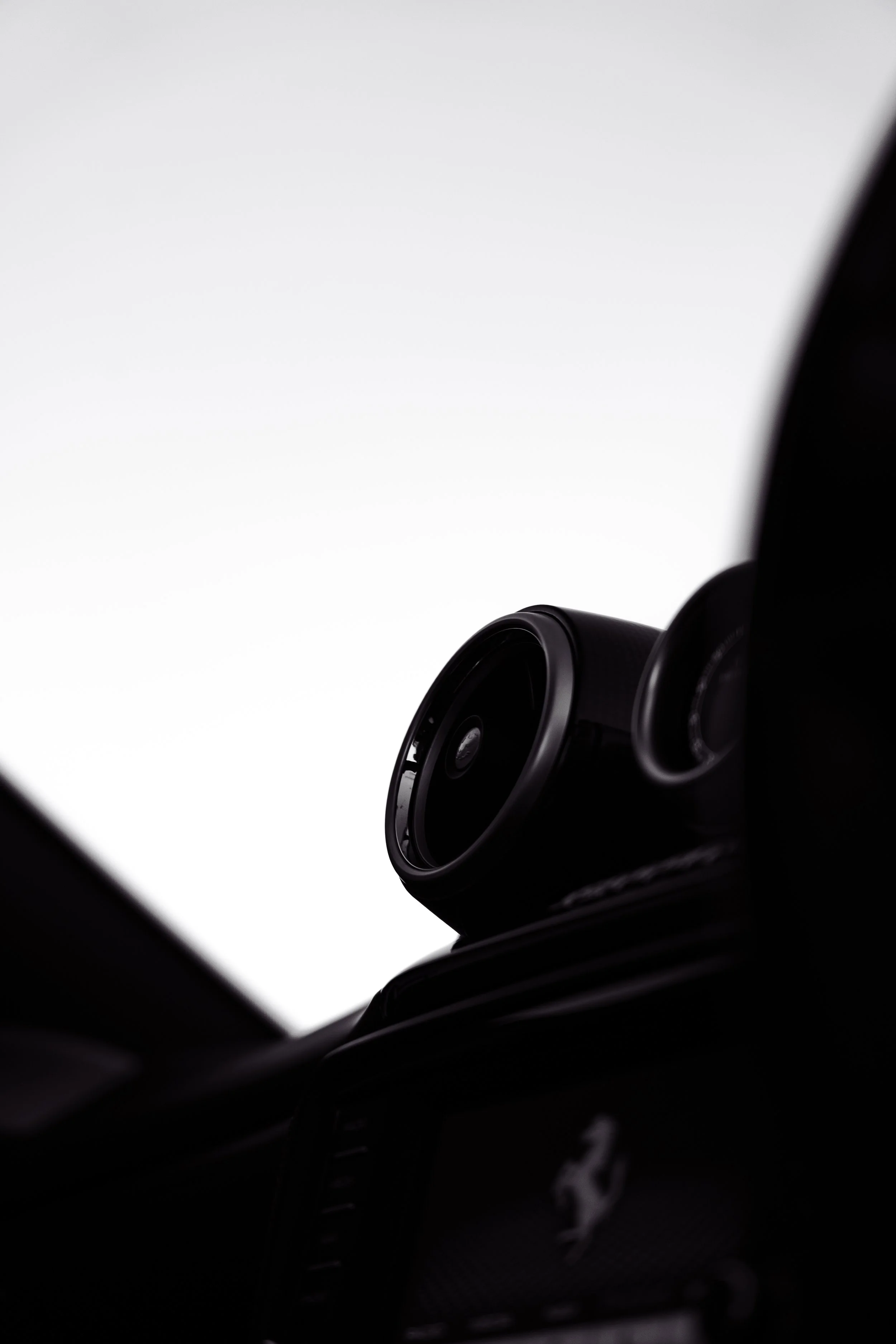 Close-up of a Ferrari speaker mounted on a car dashboard with the Ferrari logo visible.