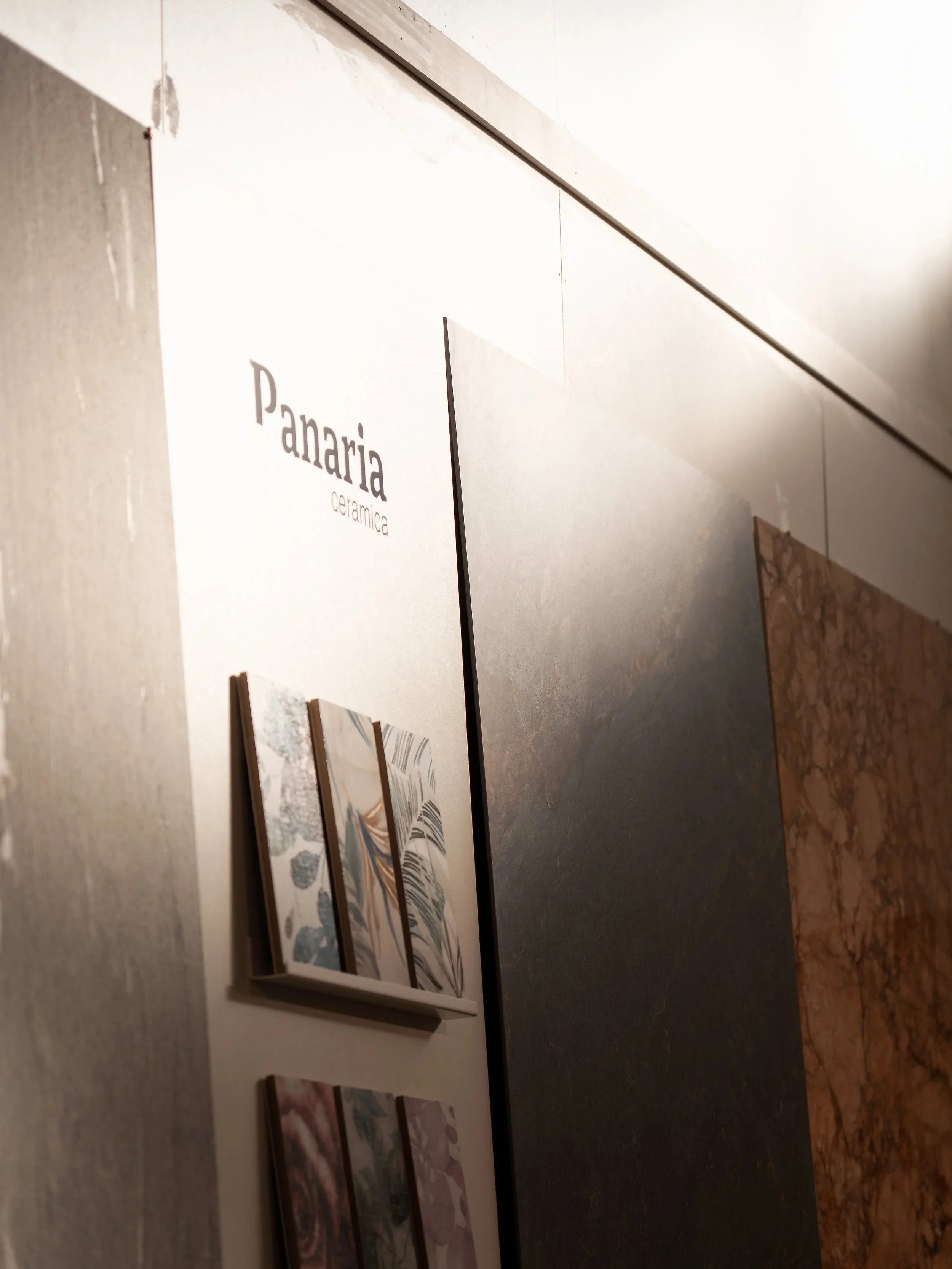 Display of ceramic tiles at Panaria showroom, featuring various patterns and textures.