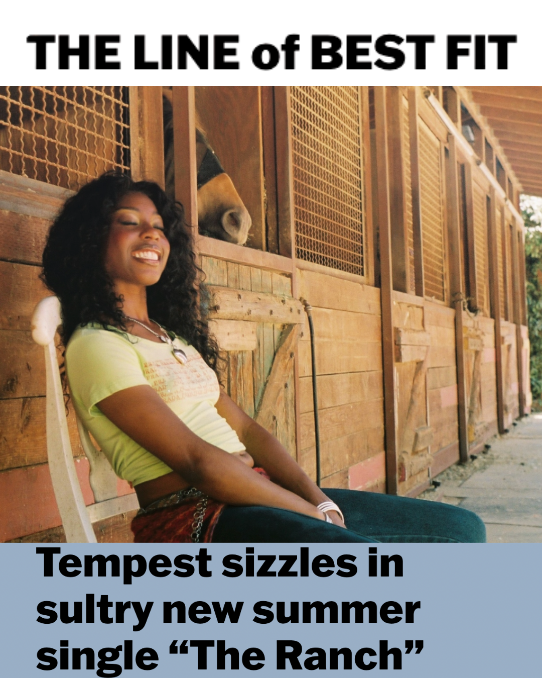 A woman sitting outside on a bench, smiling, with a horse peeking out from a stable behind her. The image has text that reads 'The Line of Best Fit' at the top and 'Tempest sizzles in sultry new summer single