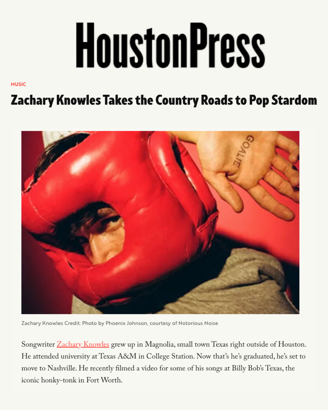 A person wearing red boxing gloves lying down, with a tattoo on their hand and wearing a brown sleeve.