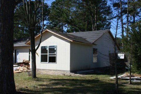 A white house surrounded by trees with a front yard and a small porch.