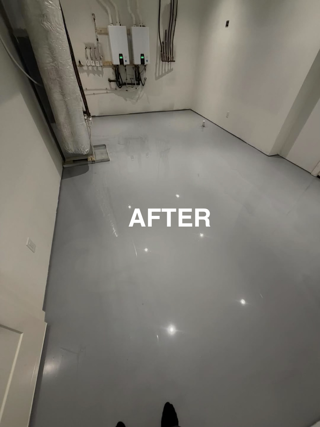 Empty room with a newly finished gray epoxy floor, labeled "AFTER". There are electrical panels and wiring on the back wall.
