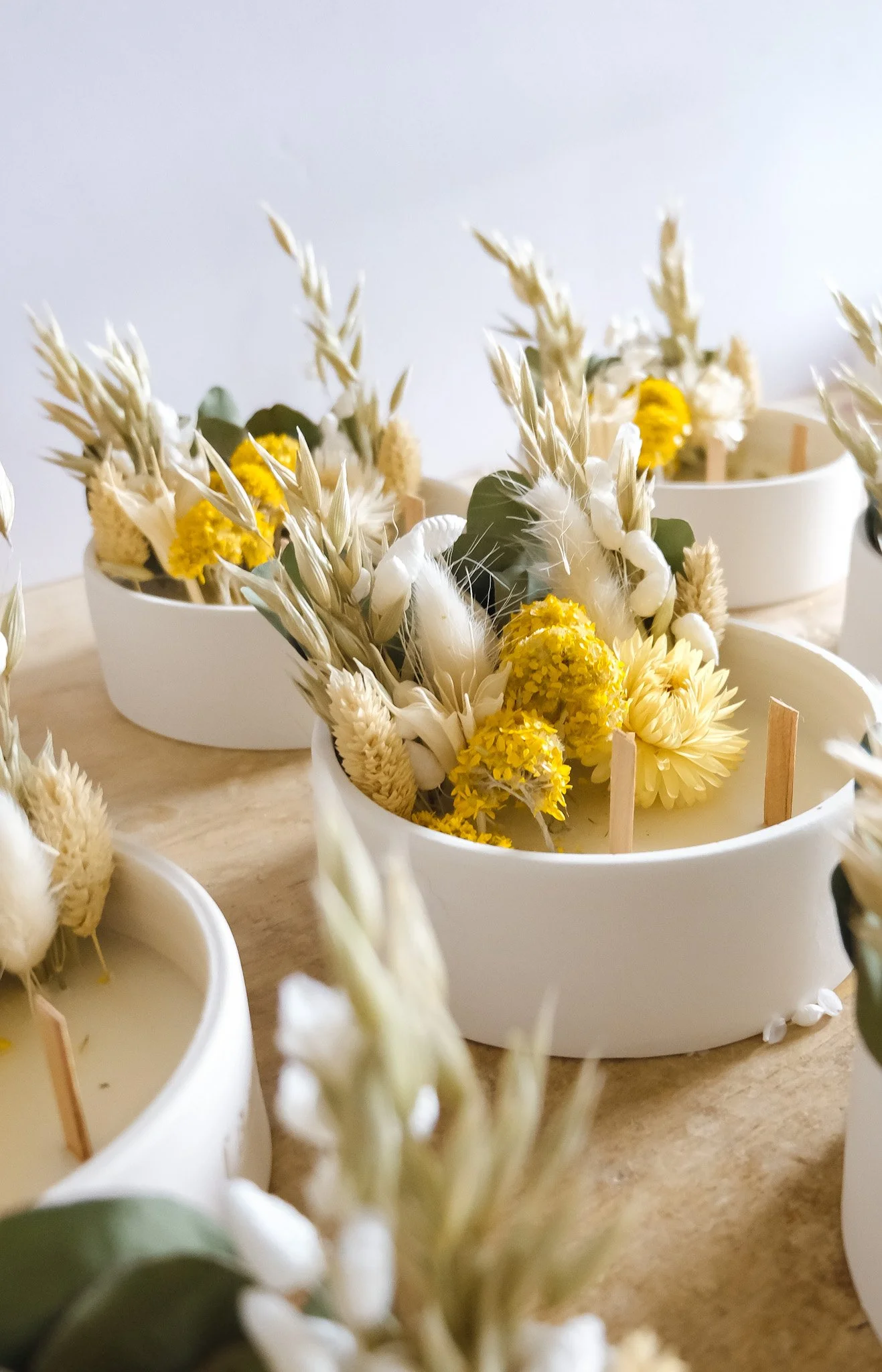Bouquets de fleurs jaunes et blanches dans des contenants blancs.
