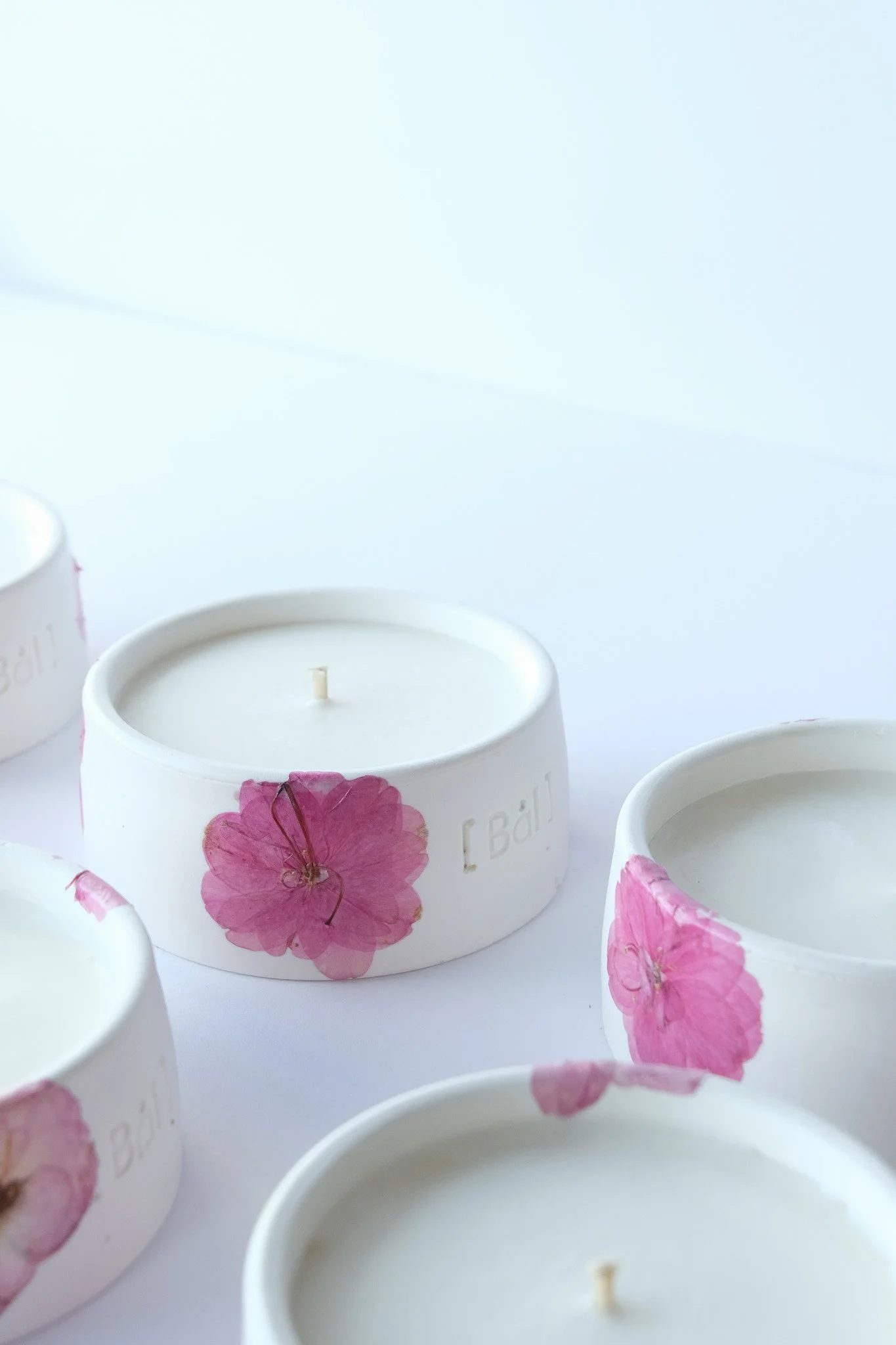 Bougie fleurs de cerisier posée sur fond bois — collection capsule éphémère Bål