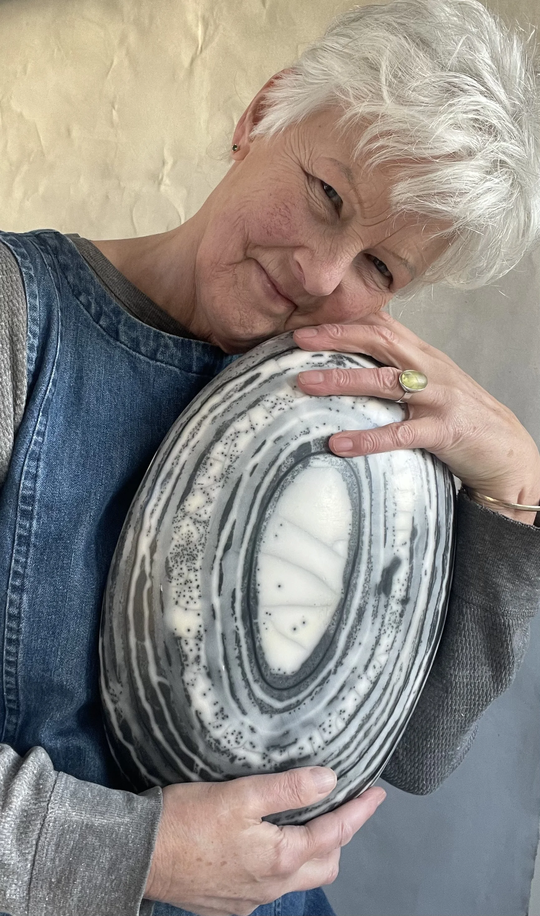 Moyra Stewart the naked raku potter is pictured wearing ba denim dress and hugging one of her large naked raku boulders