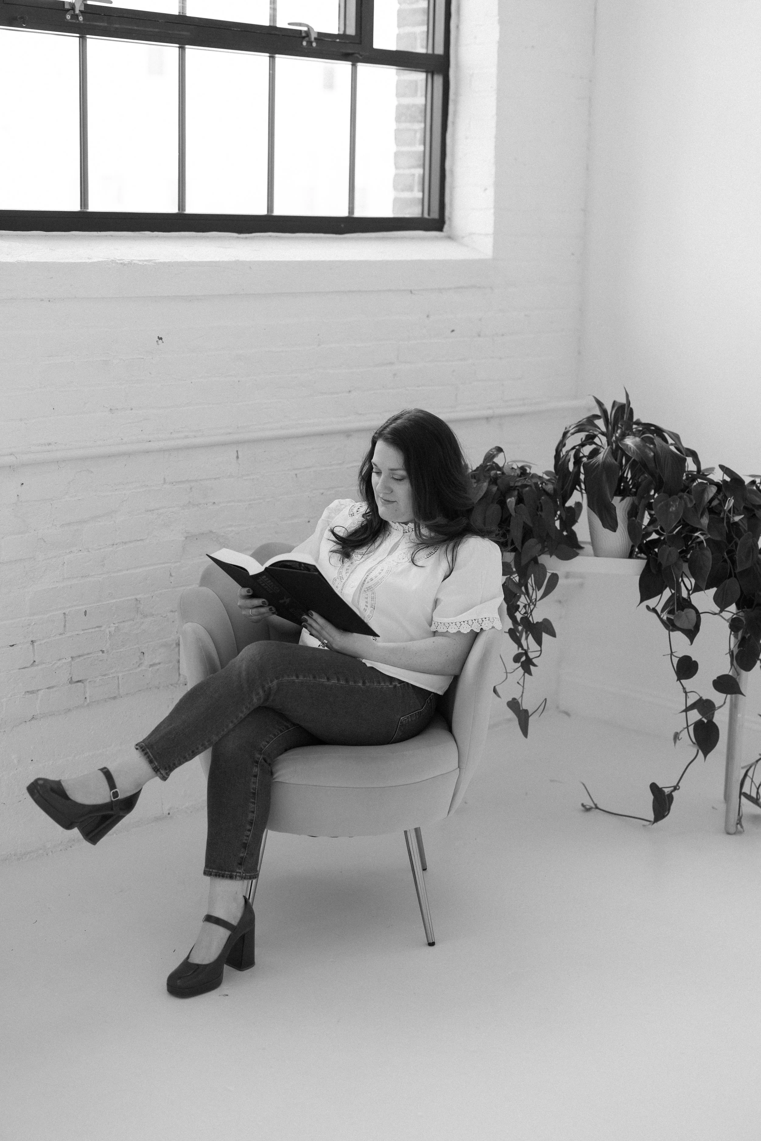 Briana Wells reading a book in a quiet, natural-light setting.