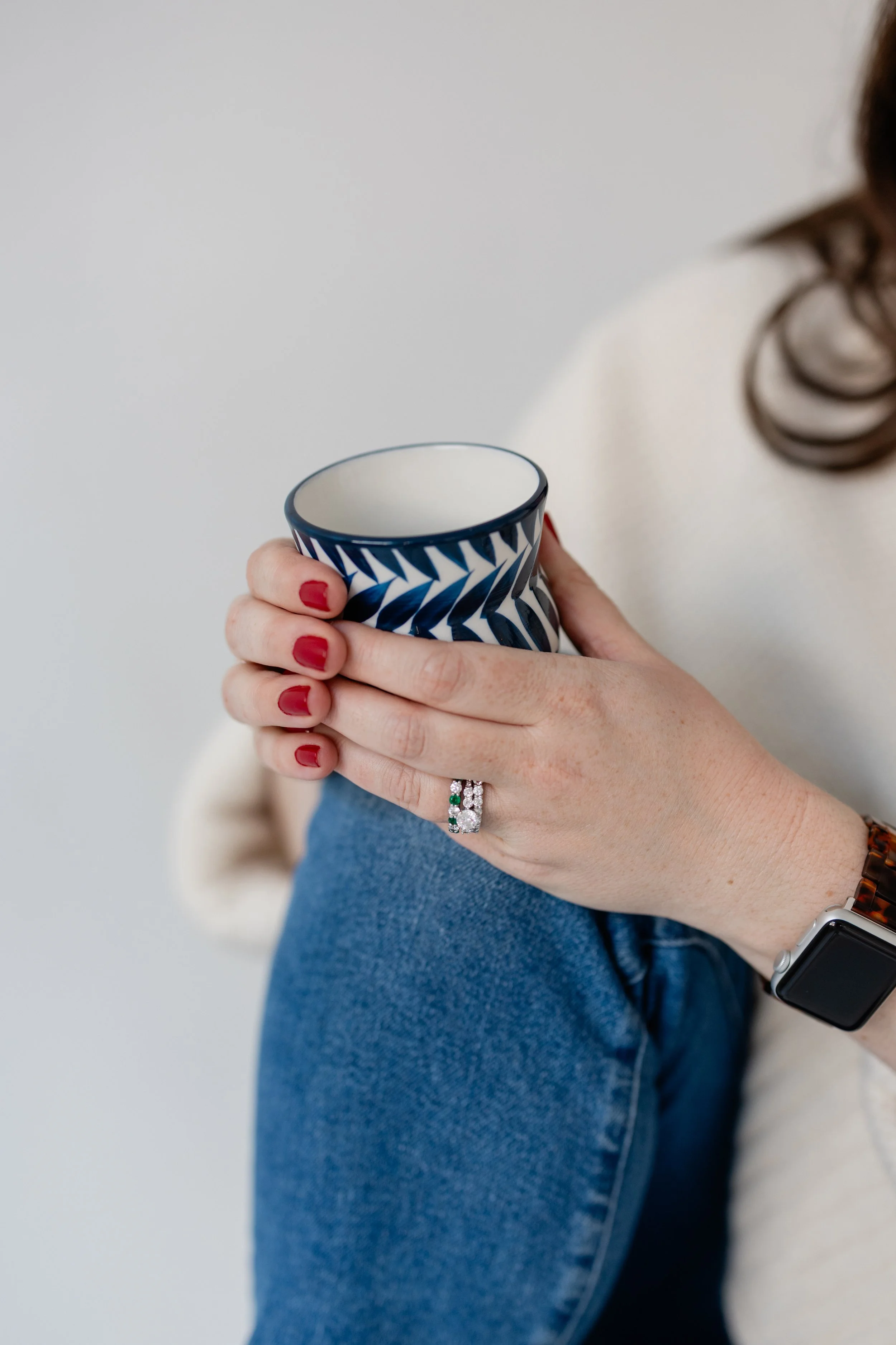 Close-up of a coffee cup held by Briana Wells in a quiet, natural-light setting.