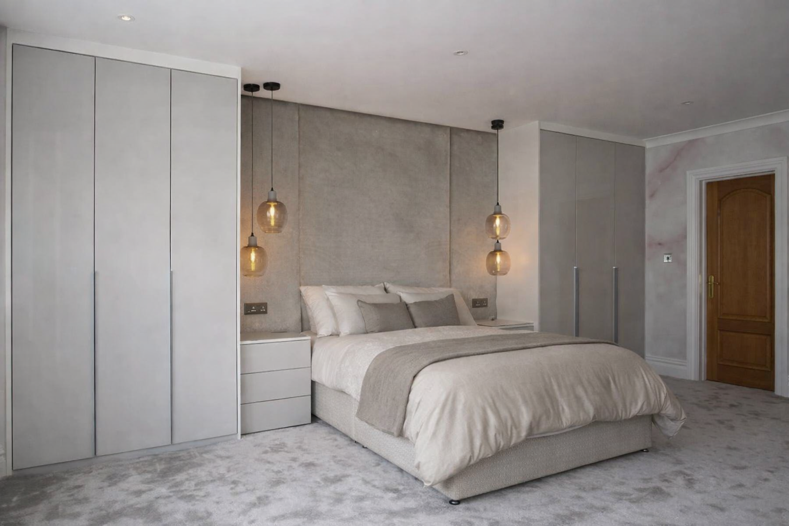 Modern bedroom with beige bedding, gray cushions, hanging pendant lights, built-in closet, and wooden door