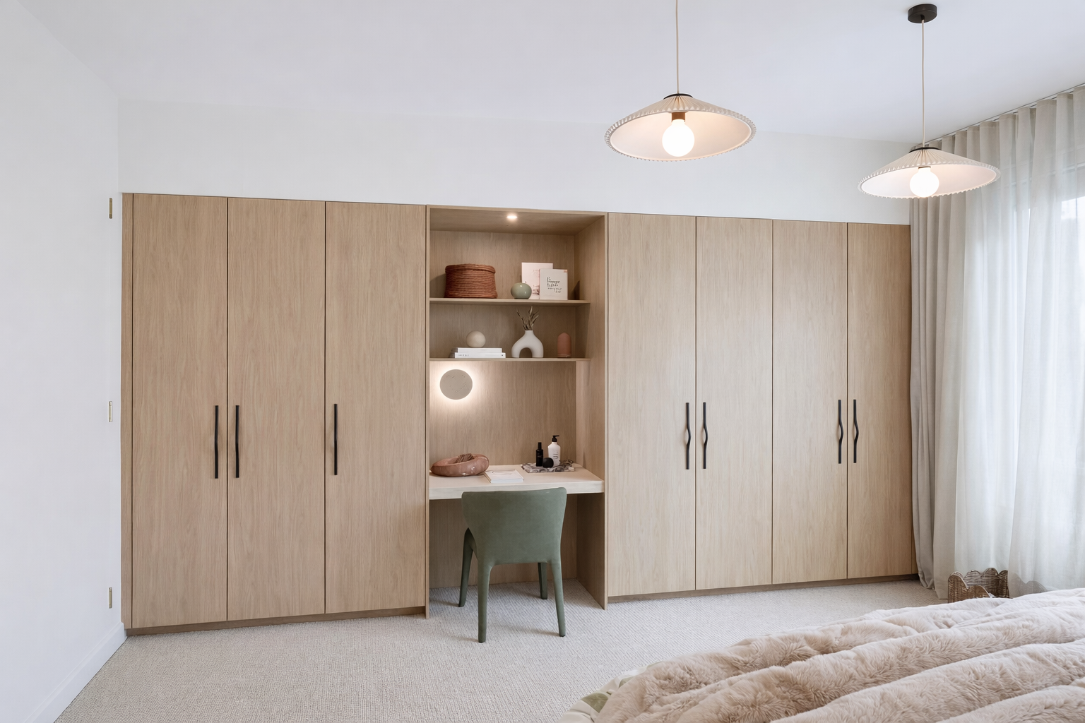 Bedroom with wooden wardrobe, small desk, green chair, and white curtains
