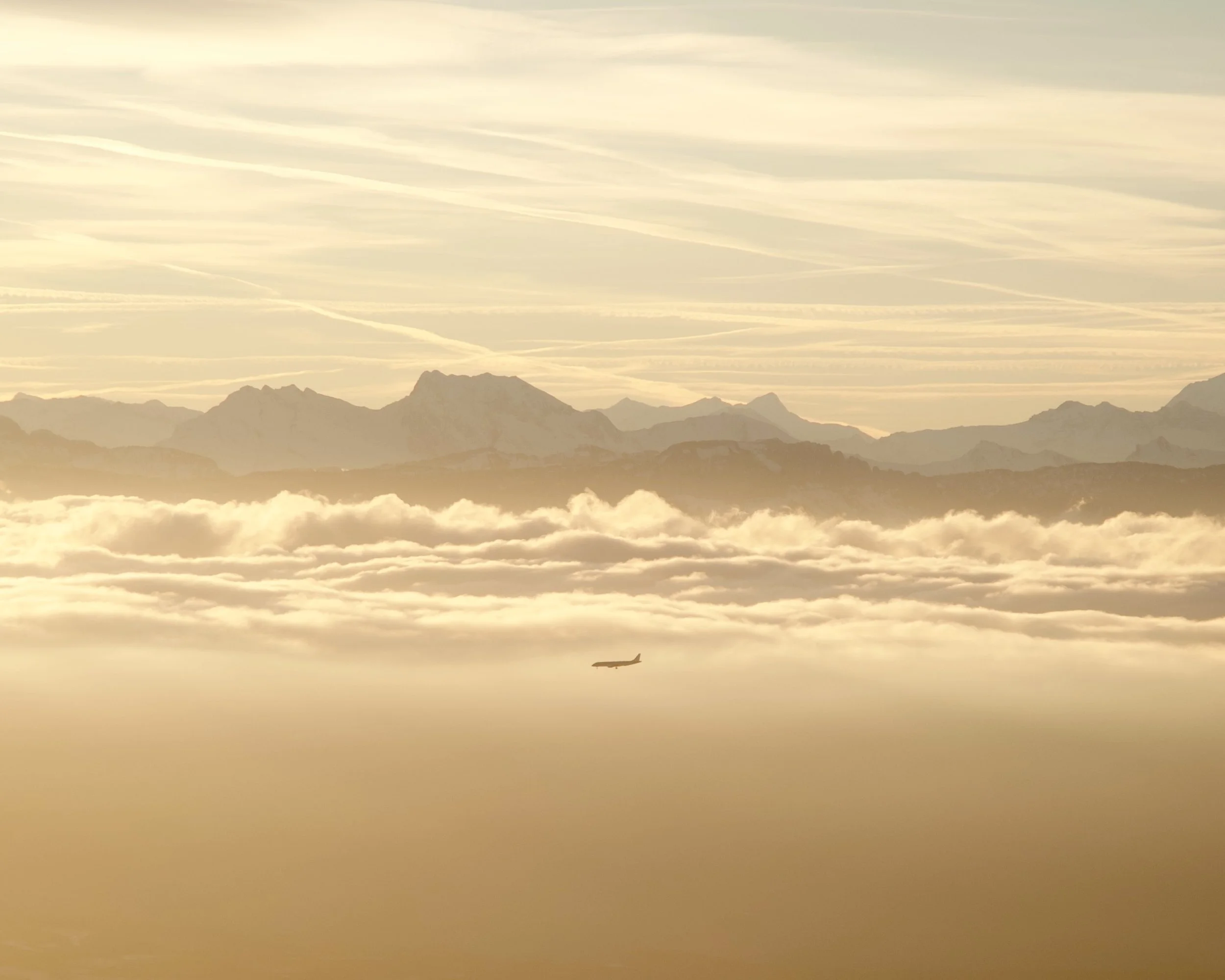 Paysage de montagnes au loin avec un avion volant dans le ciel, nuages et ciel clair