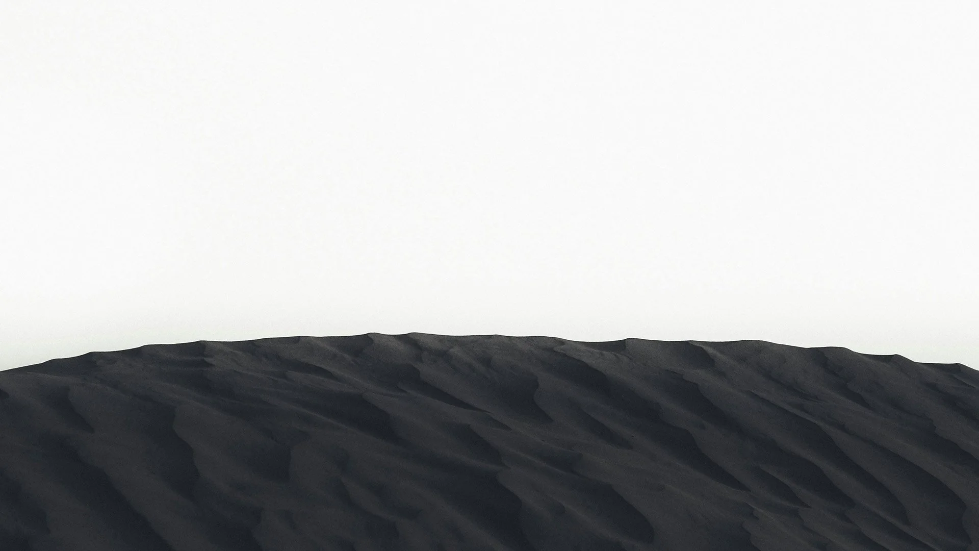 Close-up of black volcanic rocks stacked on top of each other with a clear, light sky in the background.