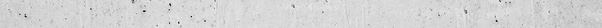 A close-up of a textured concrete surface with small black spots scattered across it.