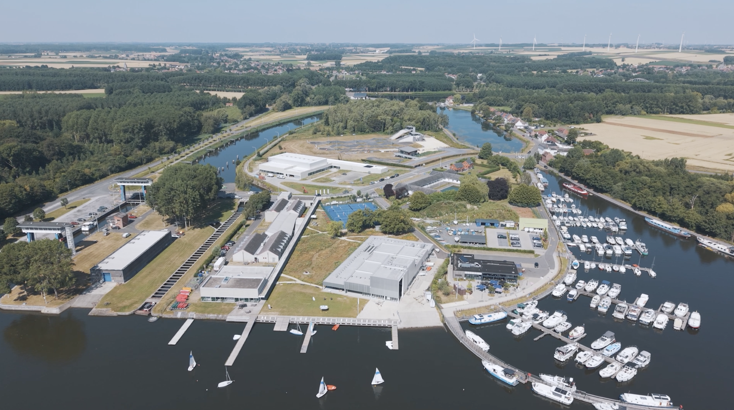 Plan d'une ville avec un lac, des bateaux, des bâtiments modernes, des arbres et des champs environnants.
