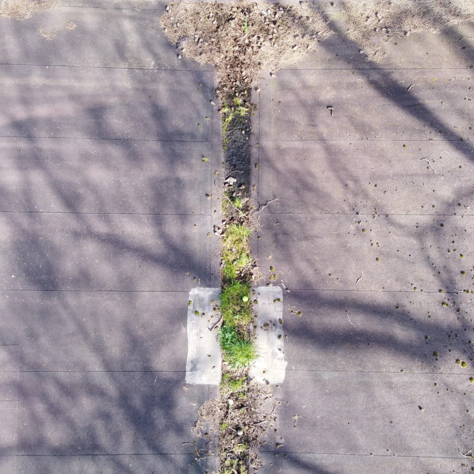 Detailed aerial view of the northern section of a butterfly roof valley showing debris accumulation and minor water ponding.