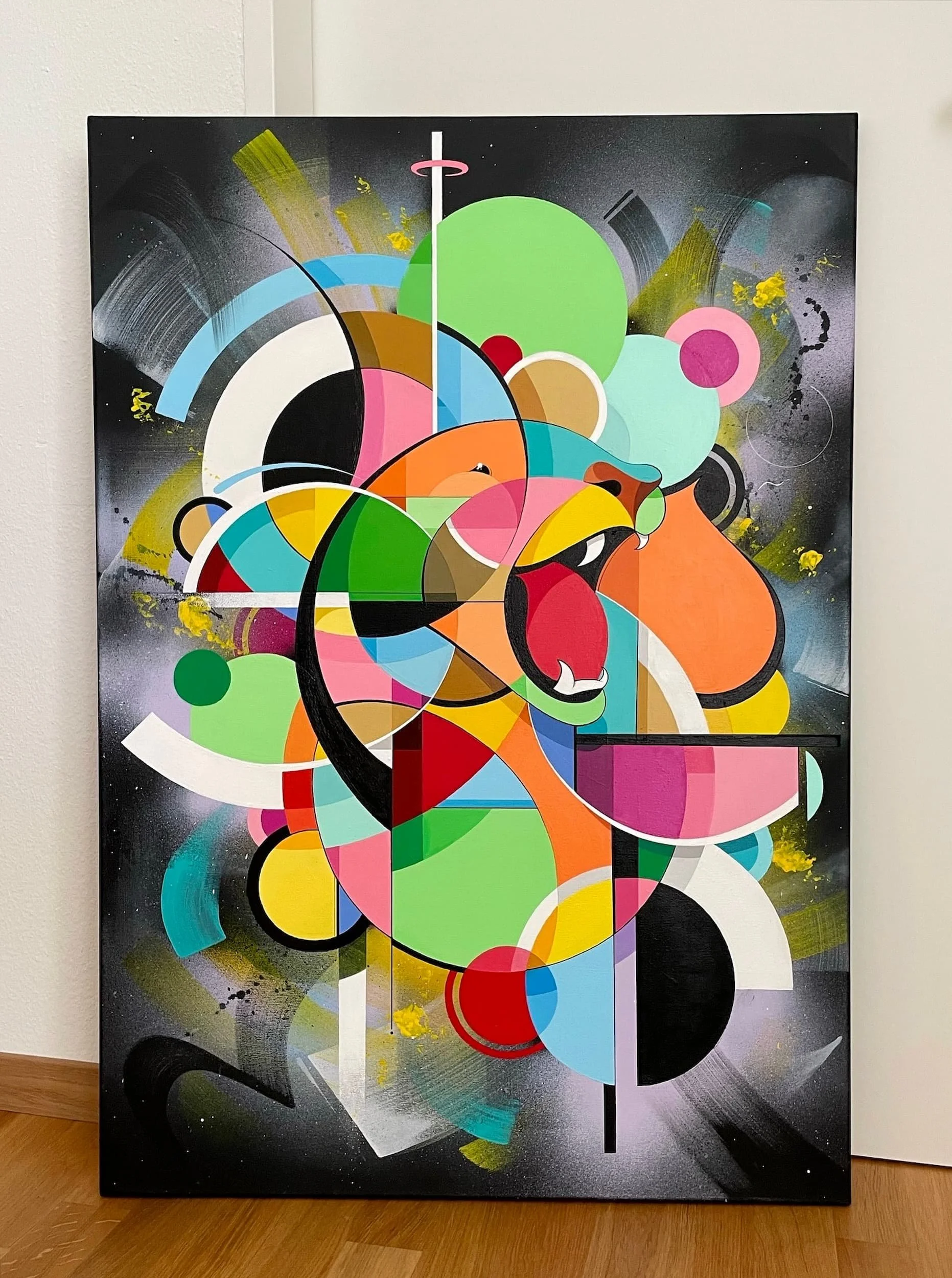 Abstract colorful mural featuring a stylized lion's face with bold geometric shapes and vibrant colors including green, orange, pink, blue, and black, with splashes of yellow and spray paint effects.