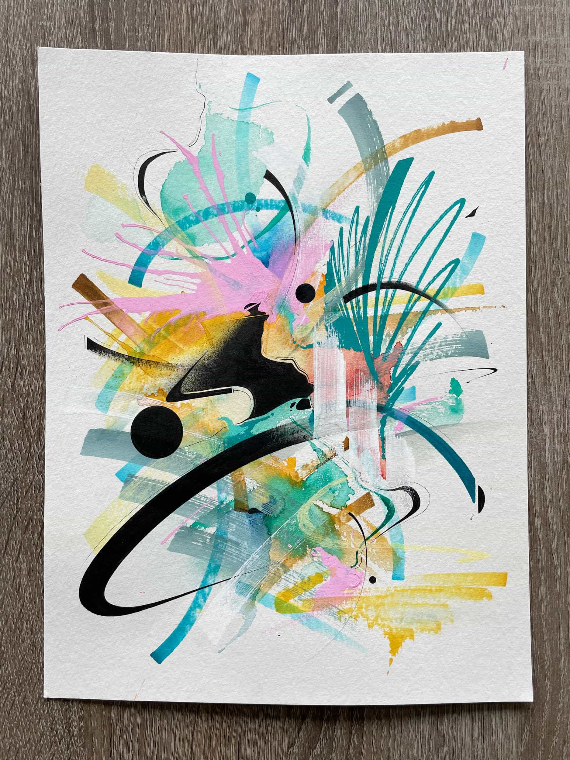 Abstract colorful painting with splashes of pink, blue, yellow, black lines, and shapes on textured white paper.