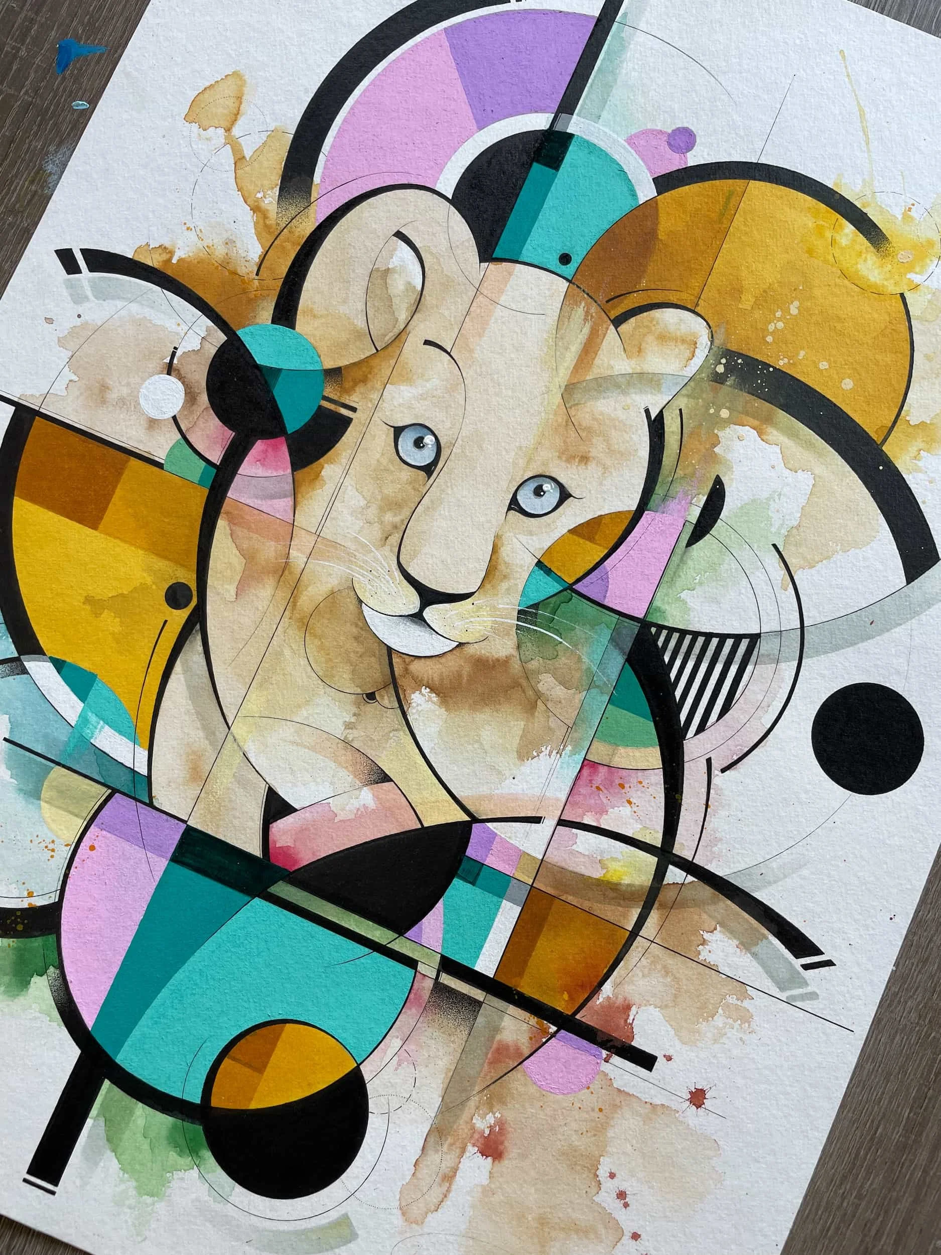 Abstract watercolor and geometric art featuring a lion's face with blue eyes surrounded by colorful circles, lines, and shapes.