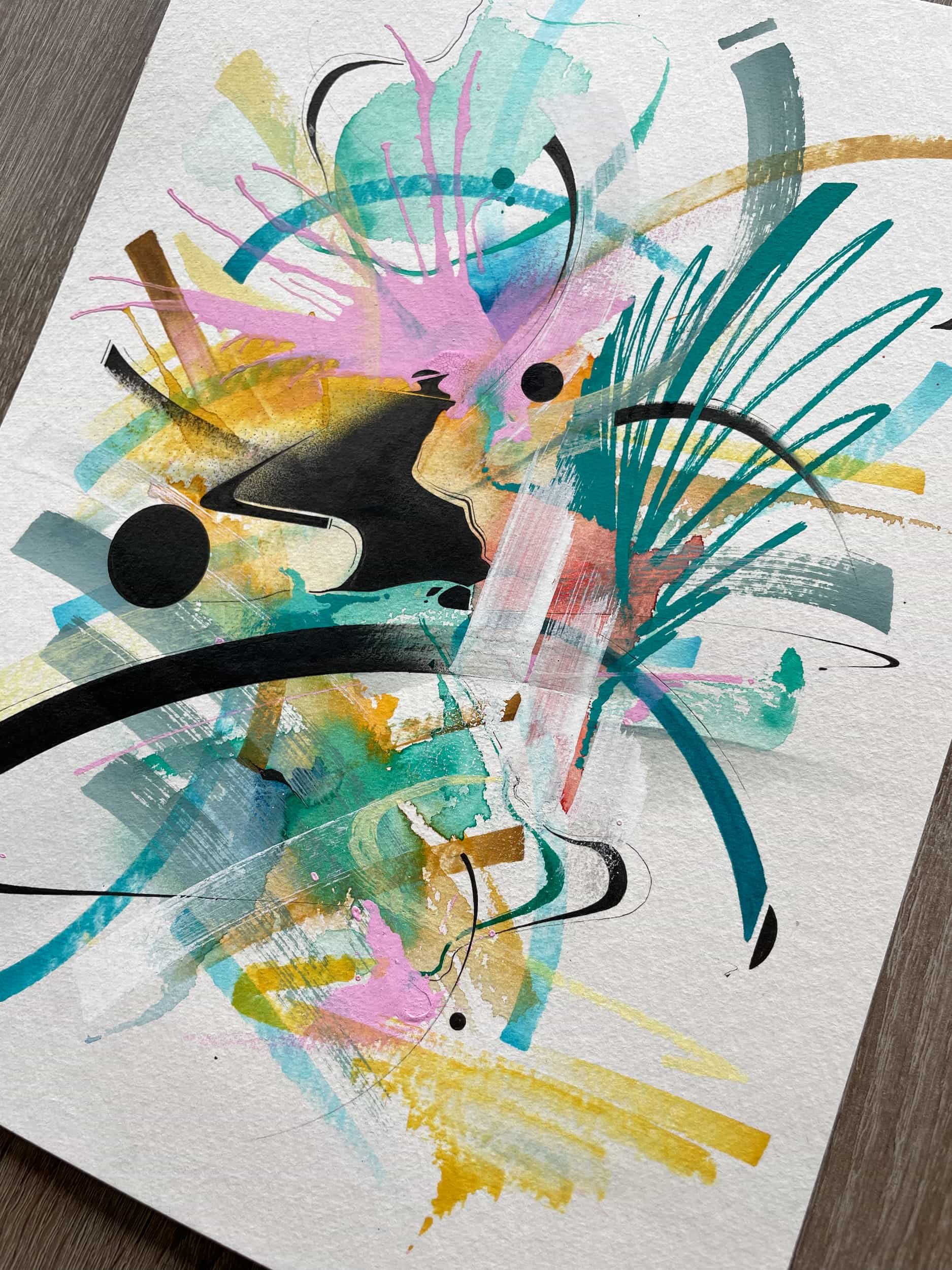 Abstract watercolor painting with splashes of pink, blue, yellow, green, black, and brown colors on textured paper.