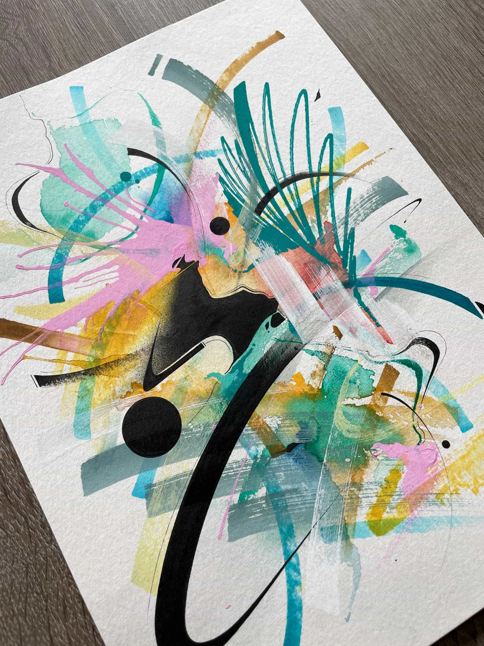 Abstract colorful watercolor and ink art with splashes of pink, yellow, teal, black, and gray on textured paper.