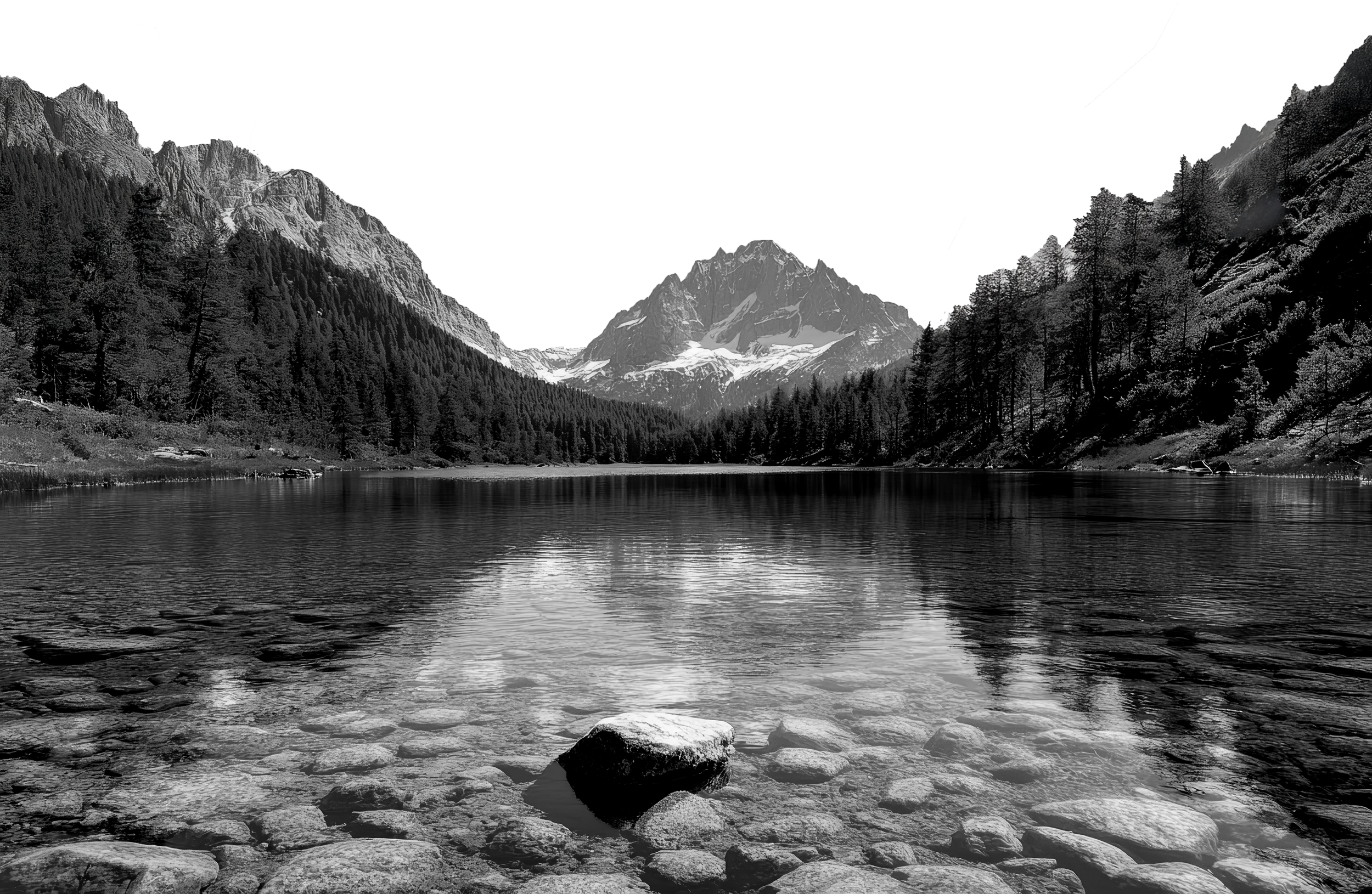 Schwarz-Weiß-Fotografie eines Sees mit Steinen im Wasser, umgeben von Wald und Bergen, mit schneebedeckten Gipfeln im Hintergrund