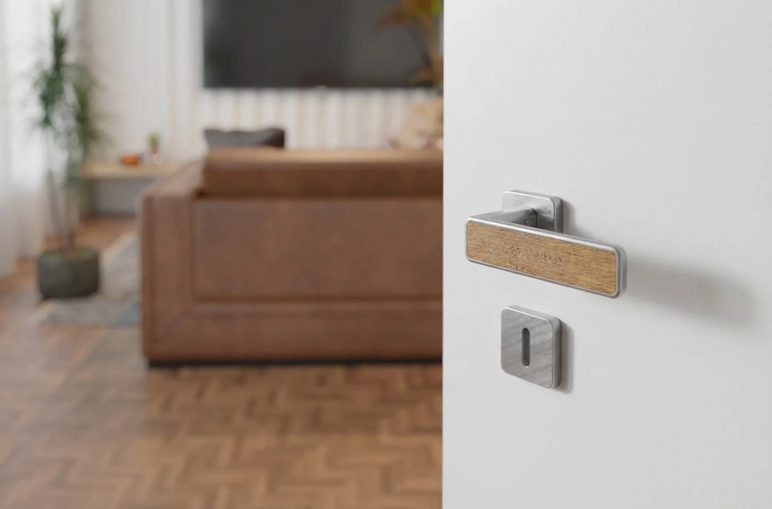 Moderner Türdrücker mit integriertem Schloss und tauschbaren Inlays an einer weißen Tür – Wohnraum mit braunem Sofa im Hintergrund