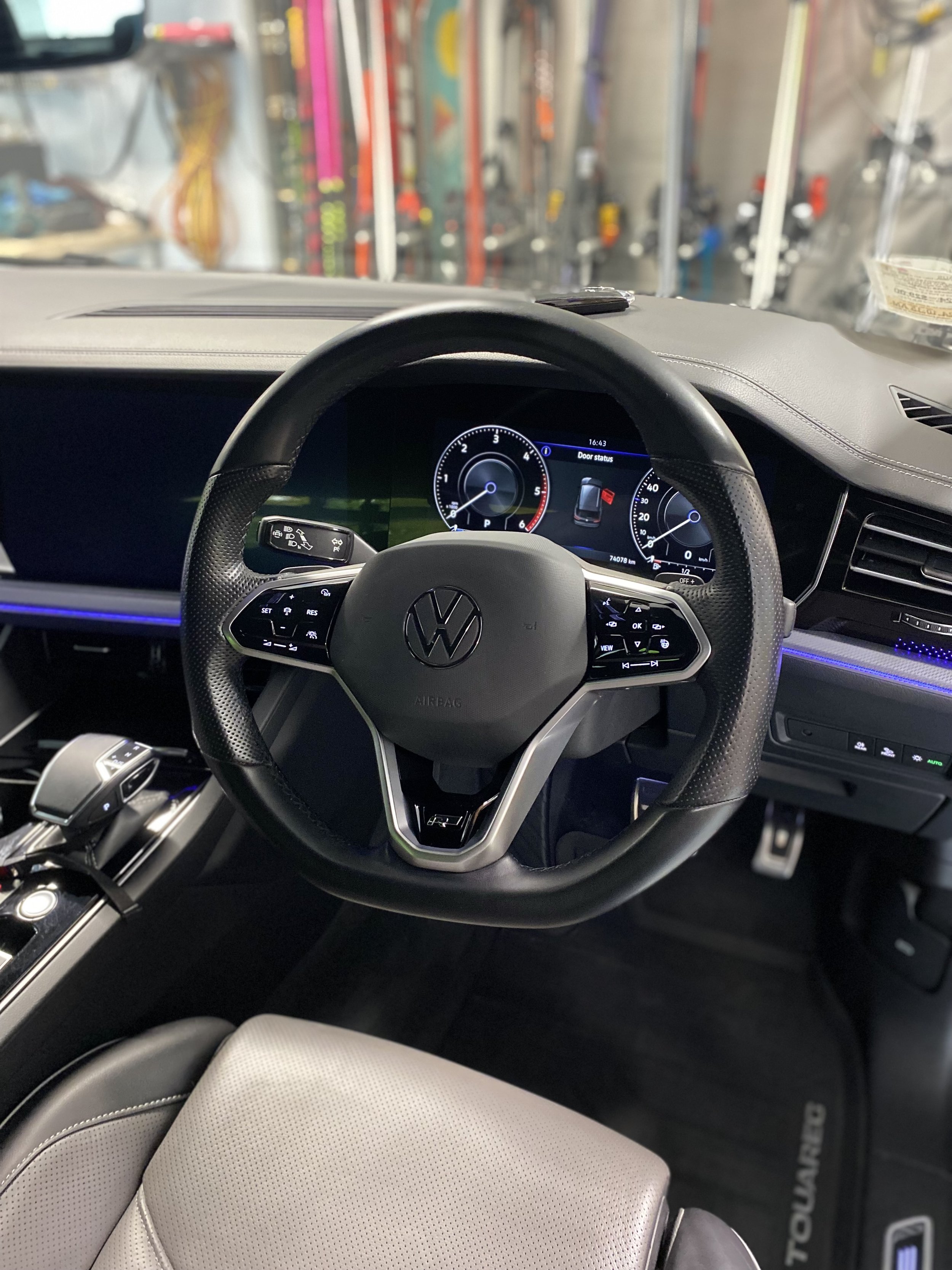 Interior view of a Volkswagen car dashboard with steering wheel, digital instrument cluster, and gear shifter.