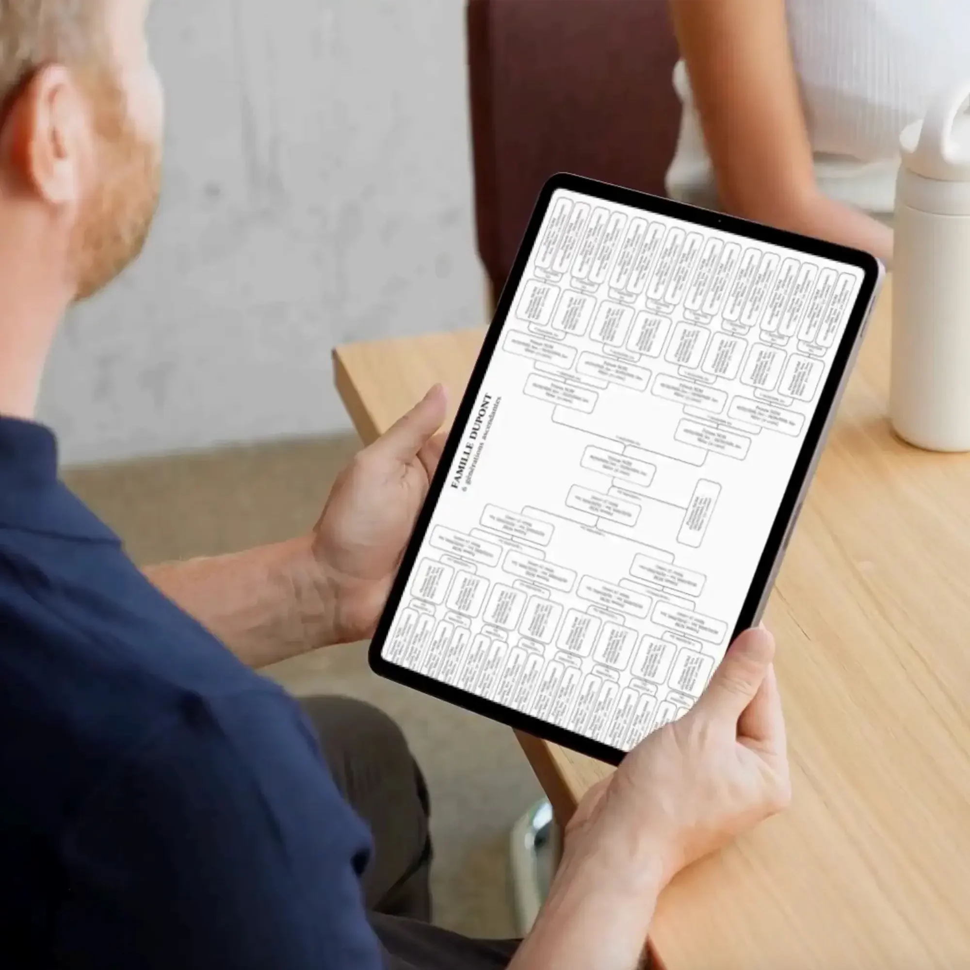 Homme tenant une tablette avec un arbre généalogique complet.