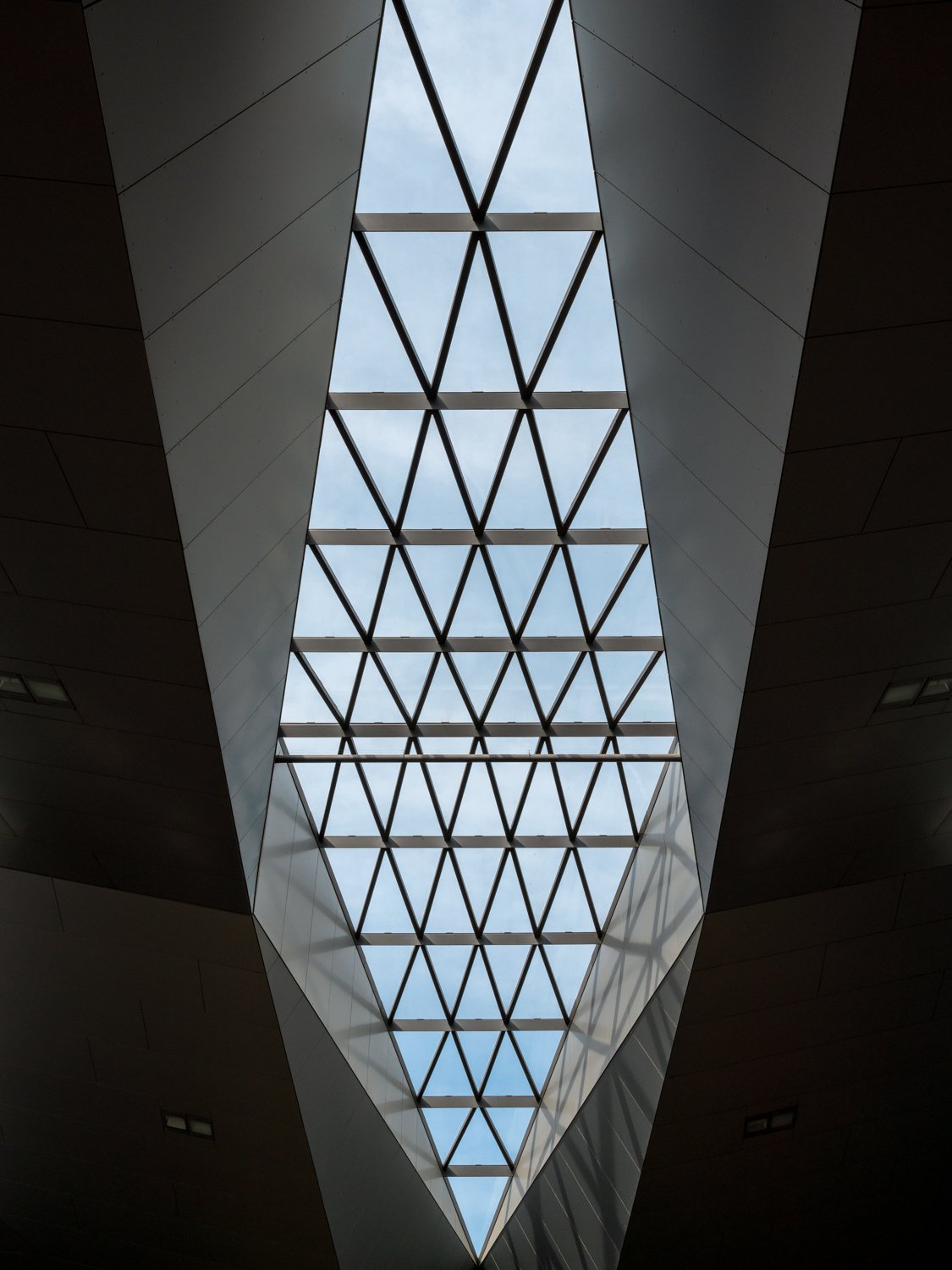 Interior view looking up at a large, geometric skylight with a diamond-shaped grid, letting in natural light.