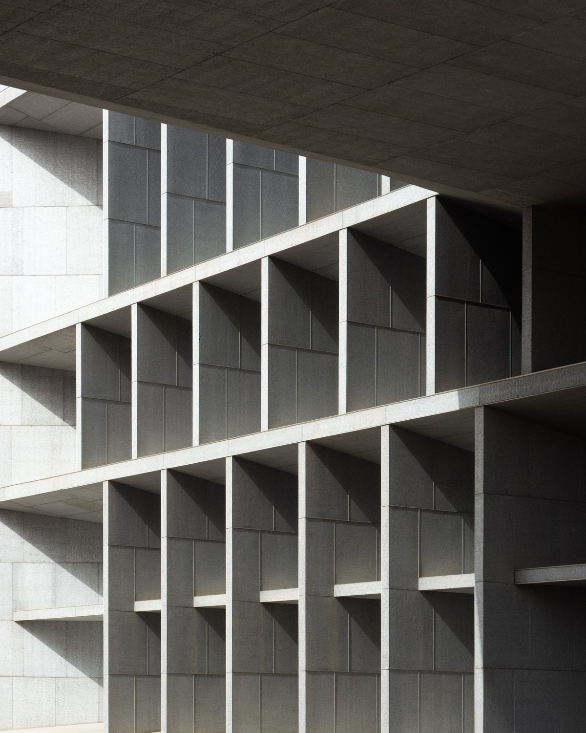 Modern concrete building with grid-like windows and shadow play.