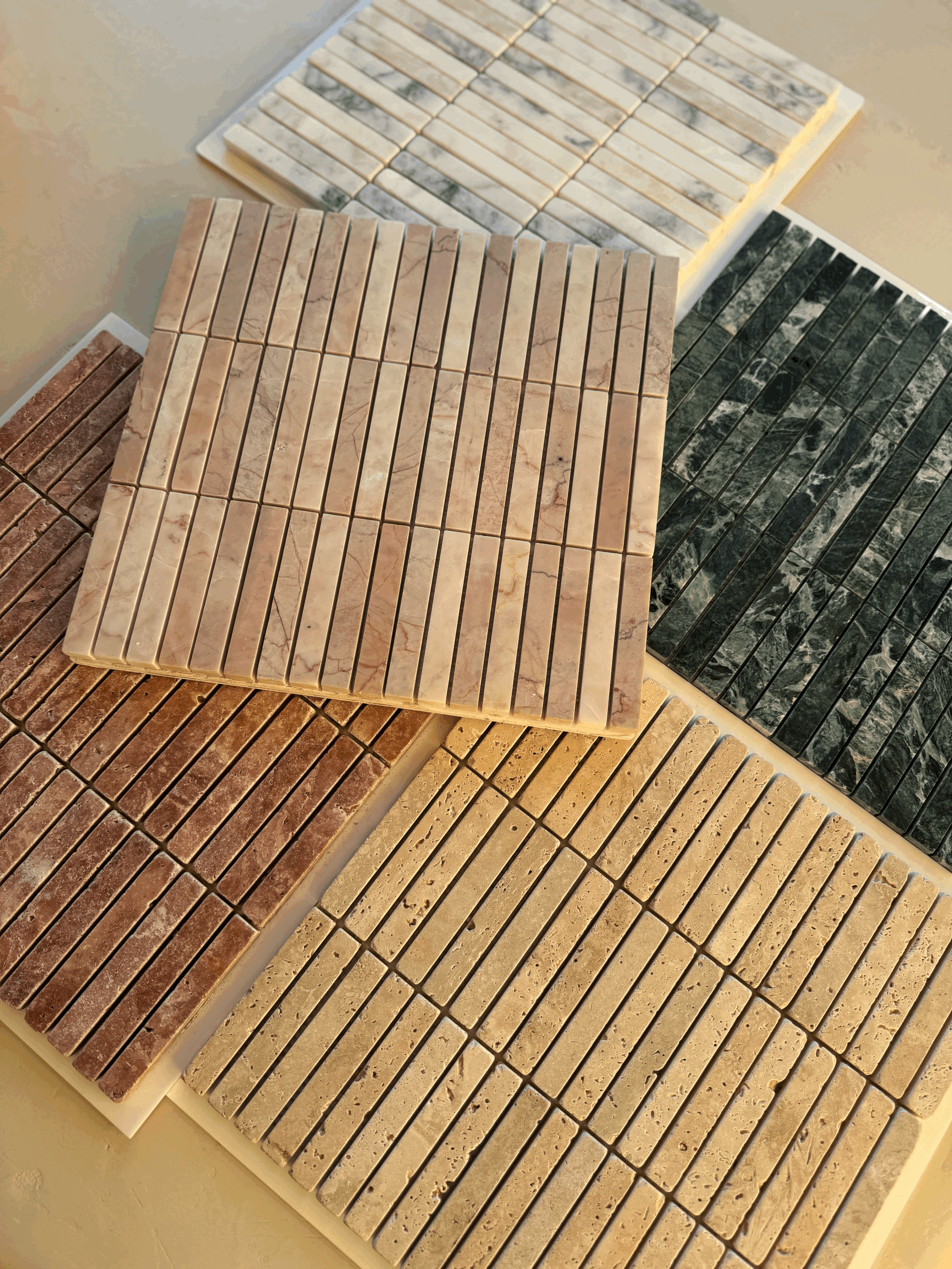 Multiple samples of marble, slate, and stone tiles arranged on a flat surface for selection or display.