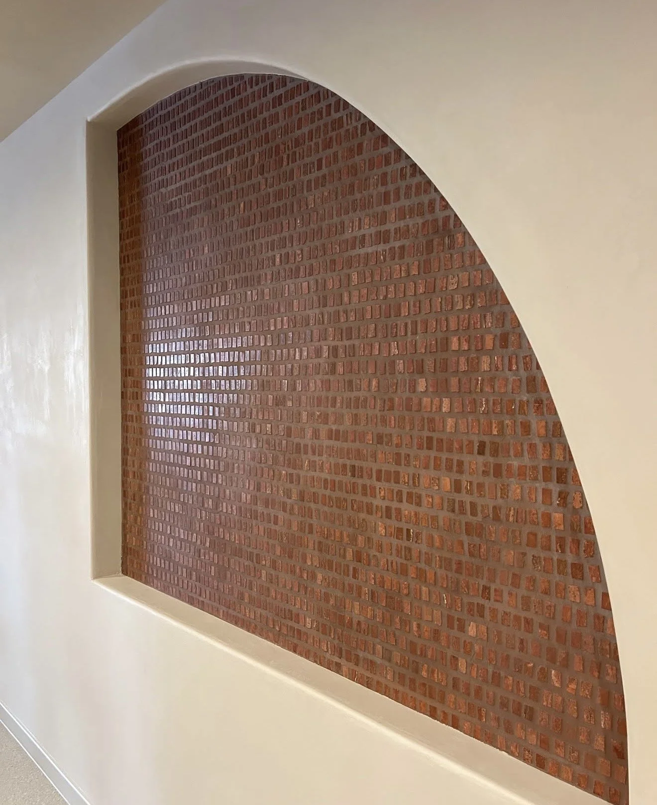 Interior wall with a brick arch and white surrounding wall.