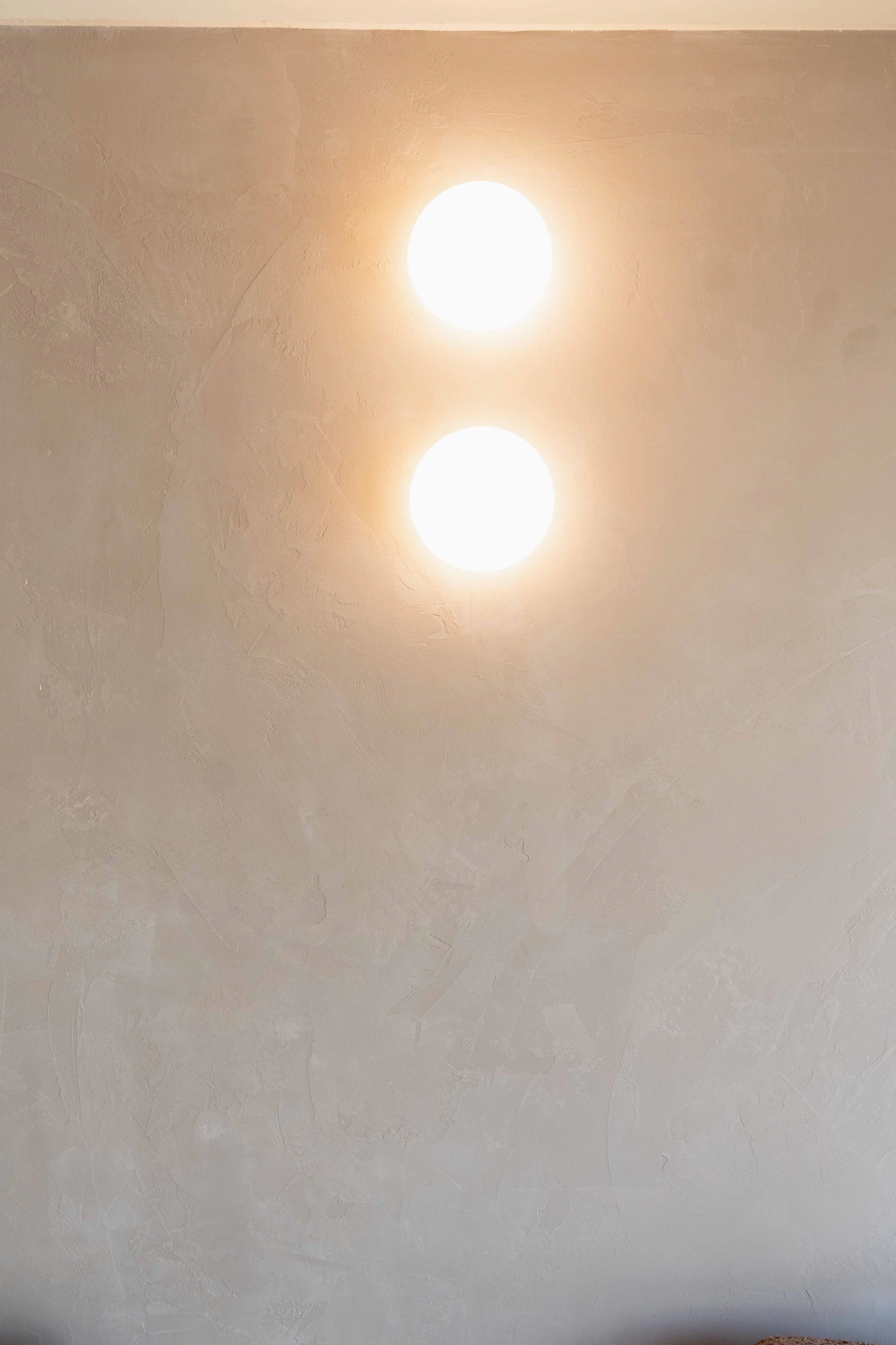 Ceiling with two bright round light fixtures on brown cerano rendered wall
