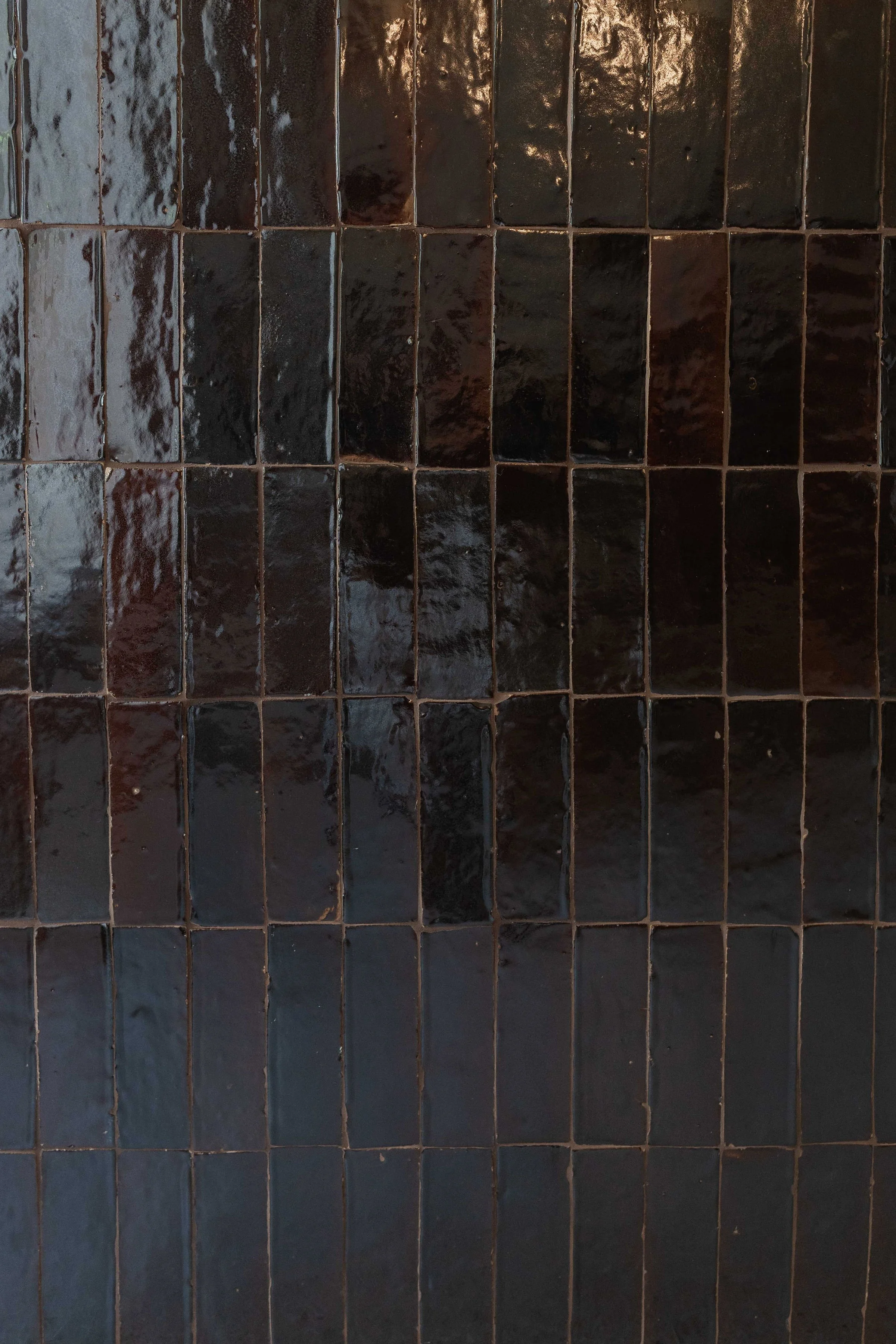 Close-up of black glossy ceramic tiles on a wall.